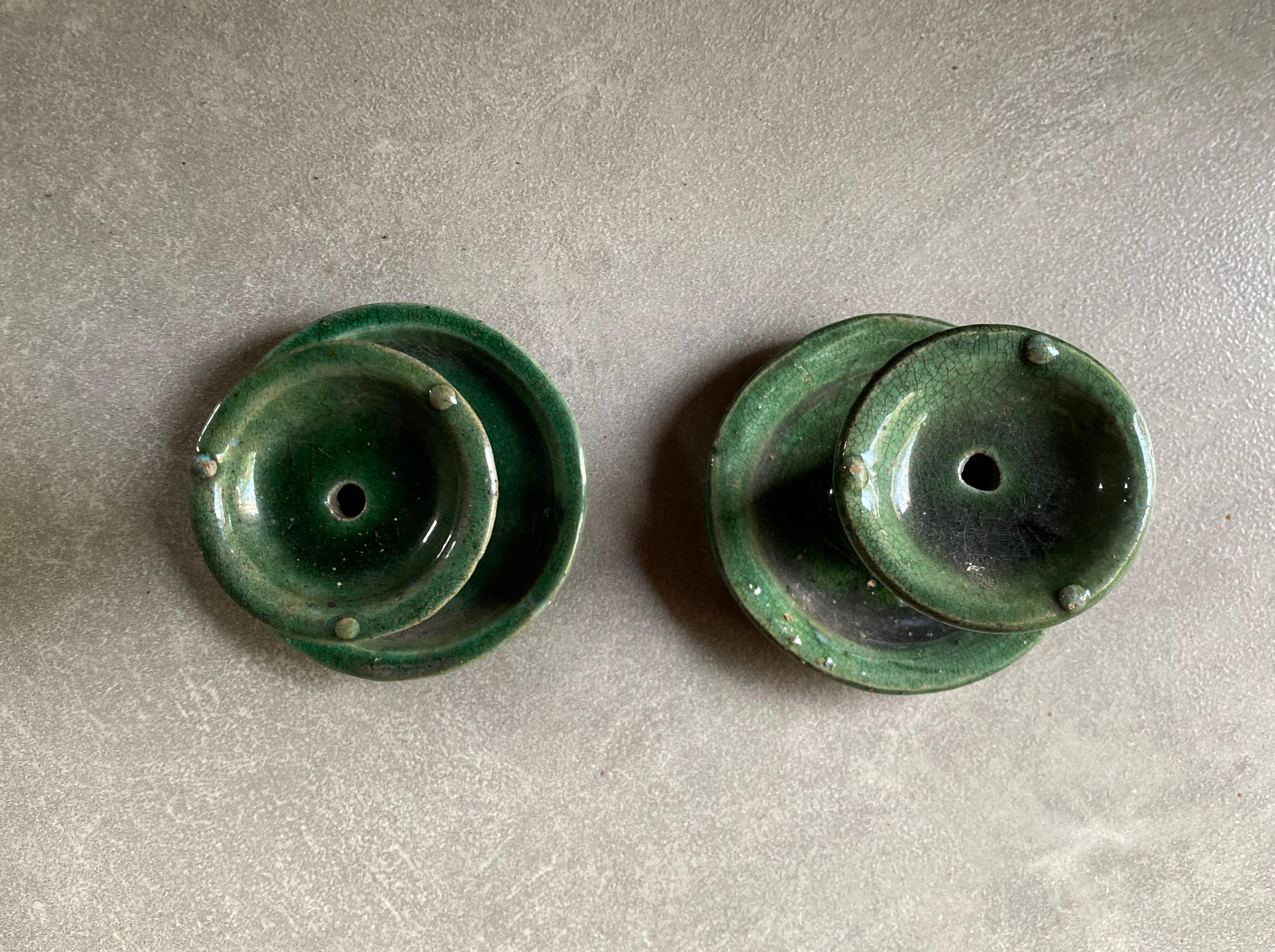 This set of Shiwan ware oil lamps from the early 20th century features the distinctive green glaze. Shiwan ware is a style of Chinese pottery from the Shiwanzhen district near Guangdong, China. This pair is small in size. 

Measures: Diameter 10cm