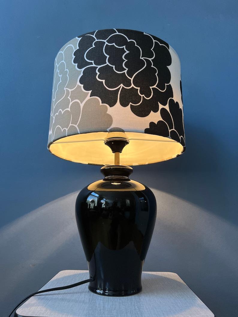 Big classic table lamp with porcelain base and hand-made black and white flower shade. The flower shade diffuses the light in a gentle and inviting manner, casting a warm and soothing ambiance that adds a touch of magic to your room. The lamp