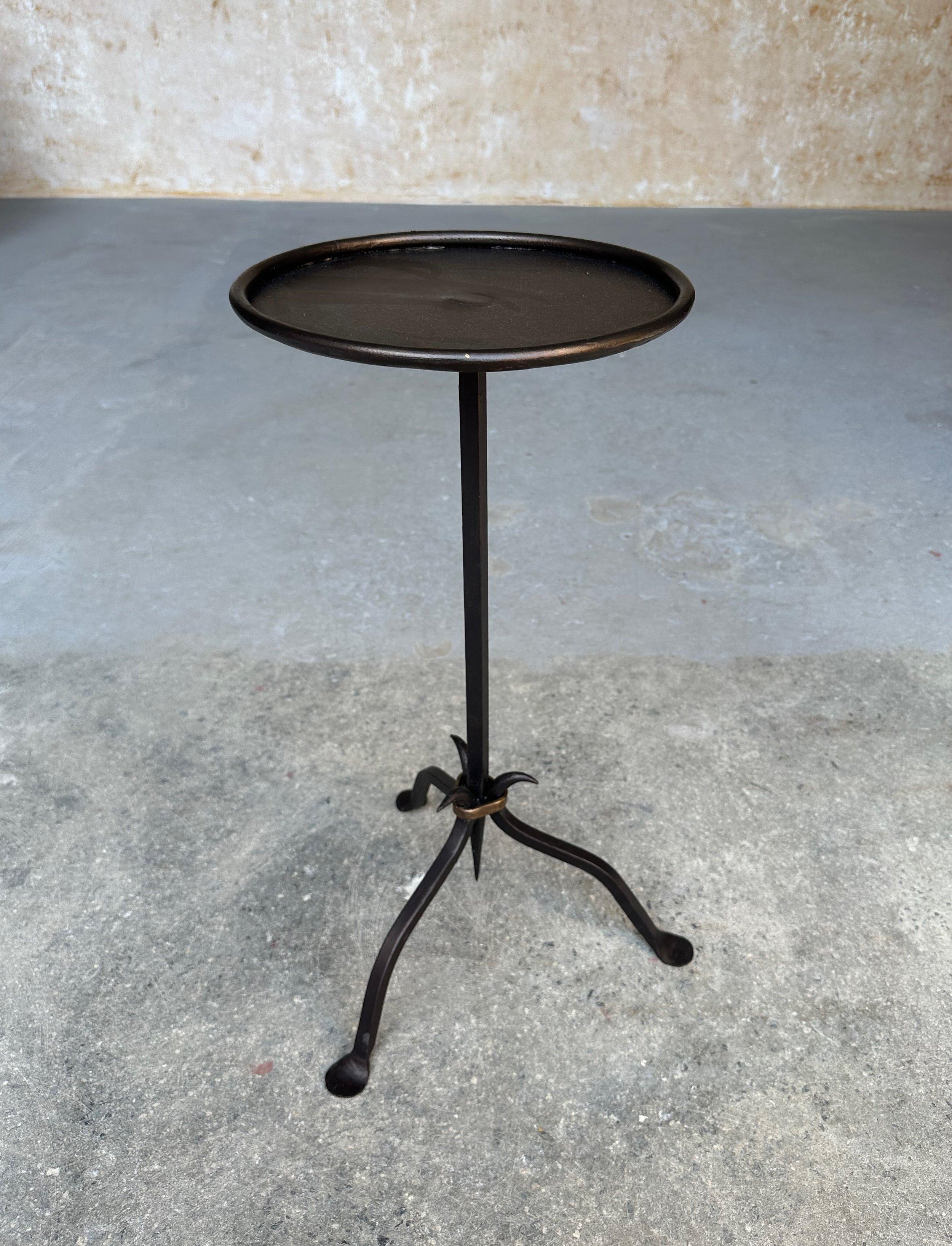This small iron and metal end table from Spain was recently crafted by skilled artisans using conventional iron-working techniques. Based on a vintage 1950s design, it features a sturdy tripod base with a central ring securing the stem that tapers
