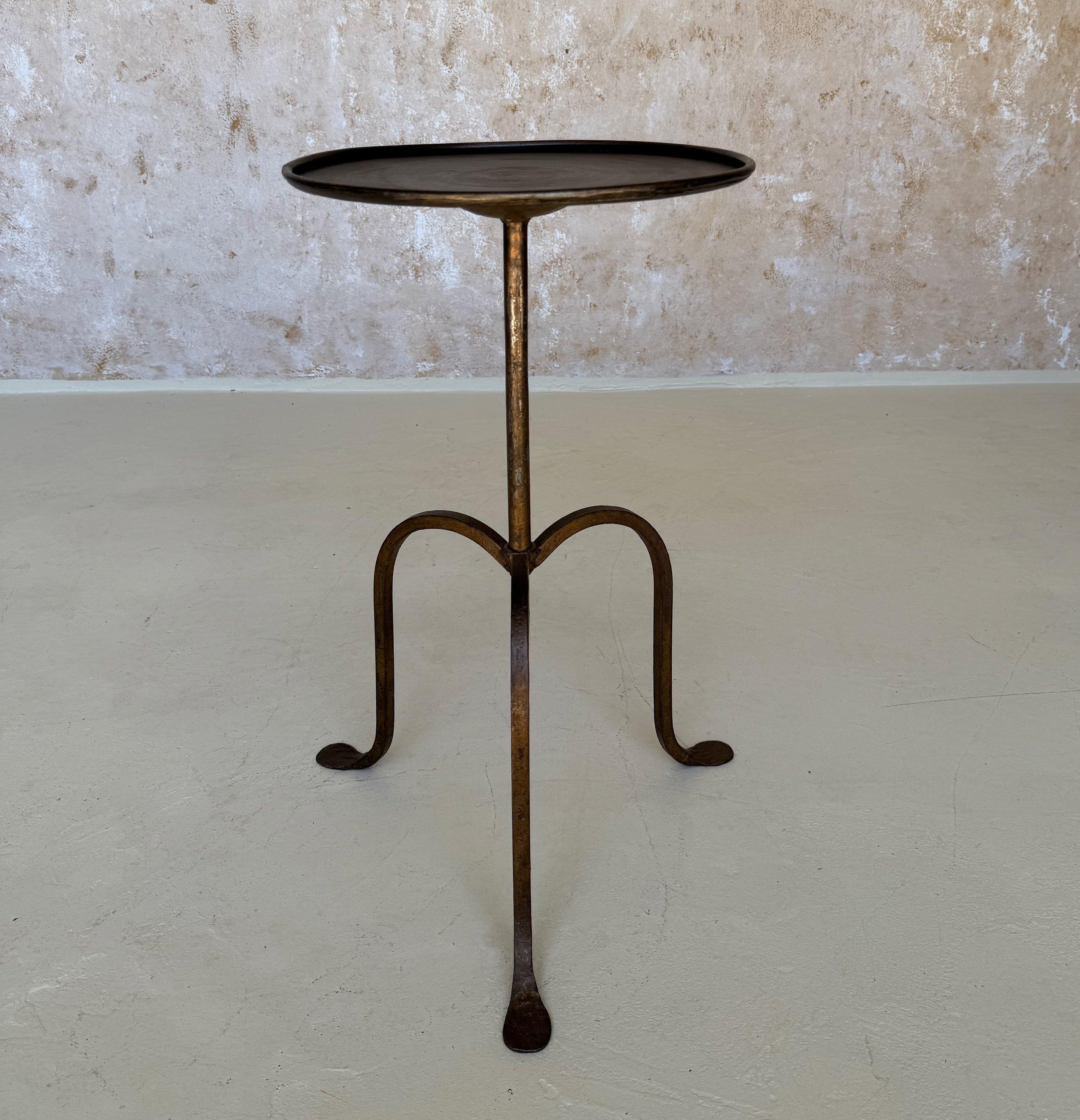 This elegant small scale side table was recently hand-crafted by European artisans using traditional iron-working methods. It features a round central stem supported by an elevated tripod base with gracefully curved legs. The original hand-applied