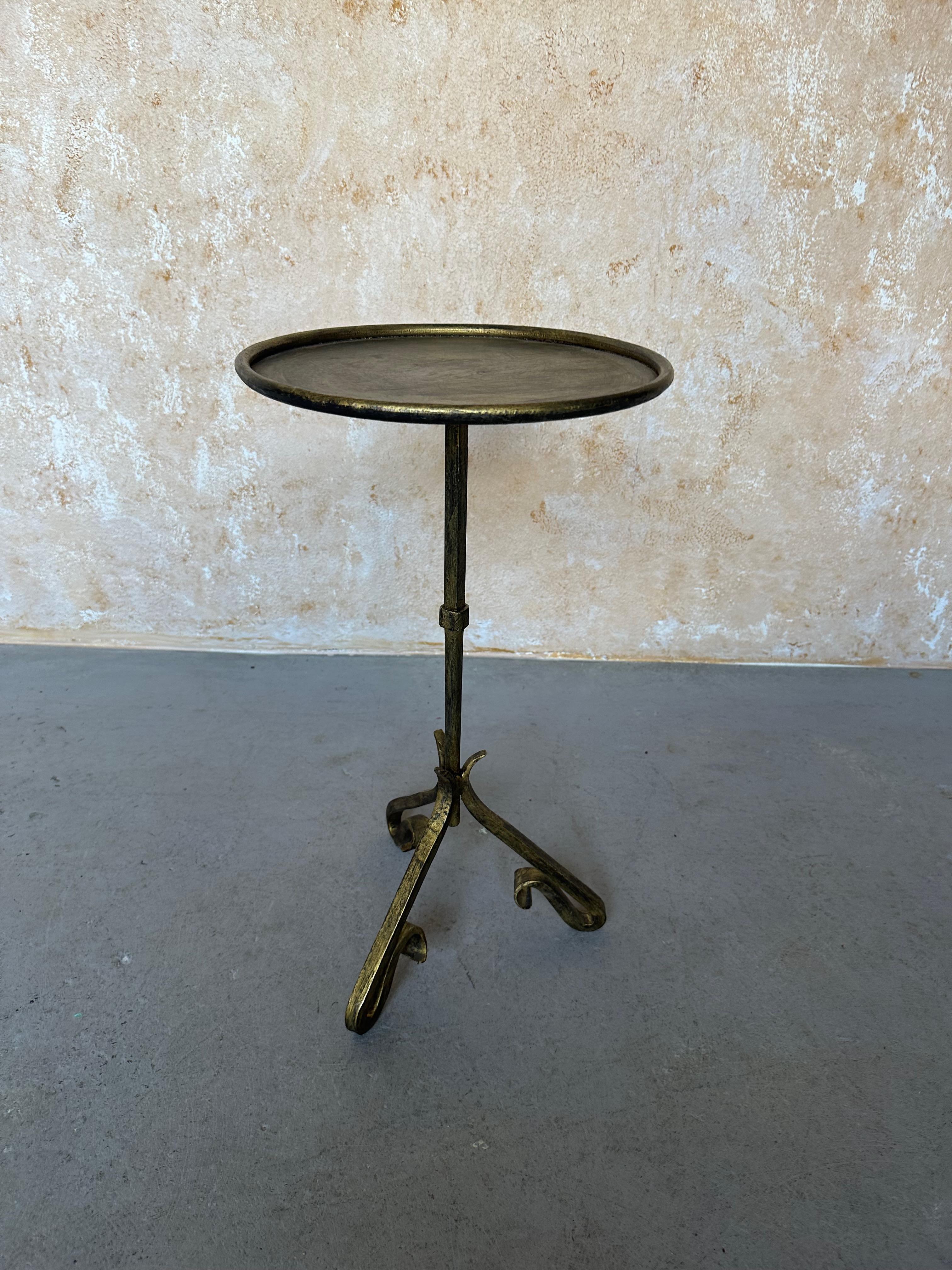 This unique small Spanish side or drinks table was recently hand crafted by skilled European artisans using traditional iron working techniques. It features a stem with a central decorative element mounted on a fanciful elevated tripod base with