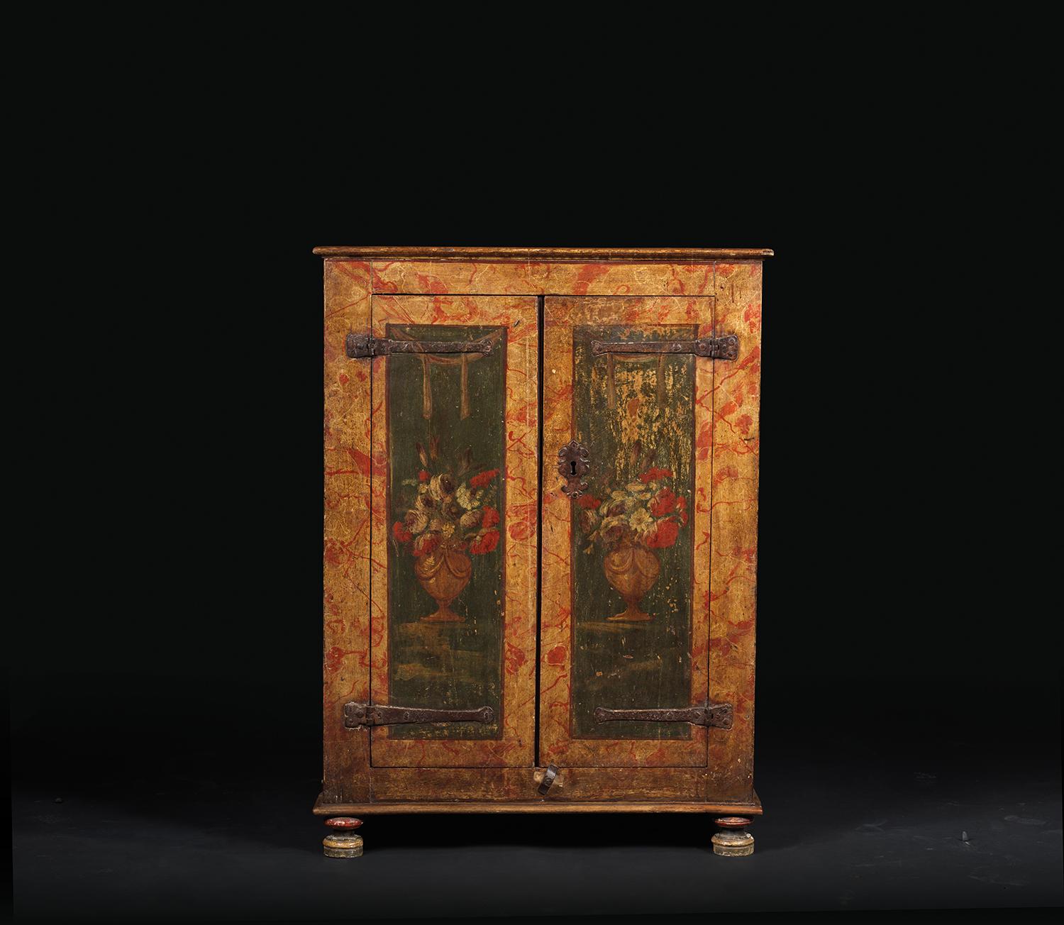 This low, small sized cabinet opens thanks two door-leaves adorned with flowers and drapes. The rest of the cabinet bears a painted decor emulating marble with red veins.