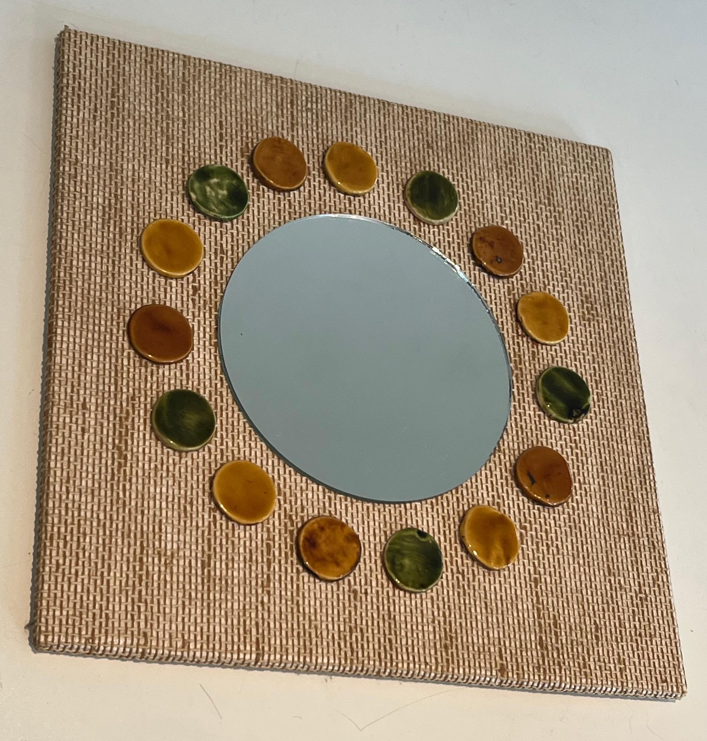 This small square mirror is made of raffia en colored ceramics round elements. This is a French work.Circa 1970