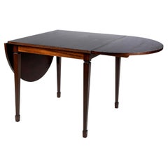 Pequeña mesa cuadrada con dos extensiones redondeadas que forman una mesa ovalada