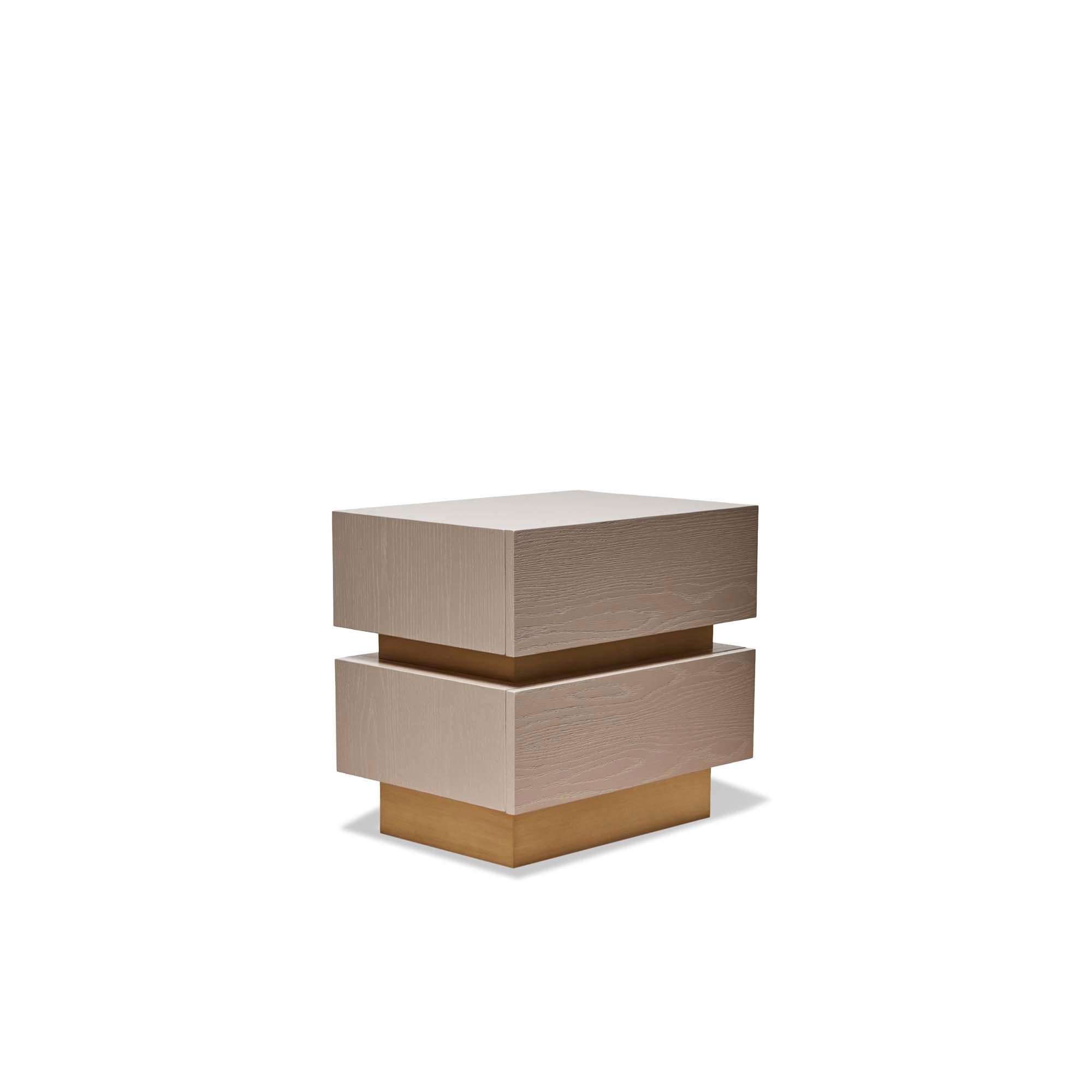 The stacked box nightstand with metal inset is a bedside table with two drawers that is available in either American walnut, or white oak and features a metal inset detail between the drawers. Available in two sizes. Show here in rocky beach
