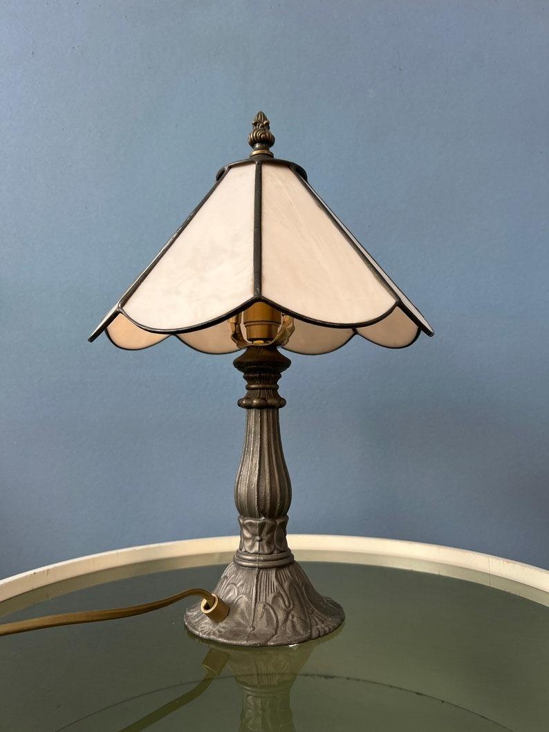 Small Tiffany desk lamp with beige stained glass shade. The base is made out of metal and the shade is made from acrylic. The stained glass produces a warm light effect. The shade can be taken off the base and positioned in any way desirable. The