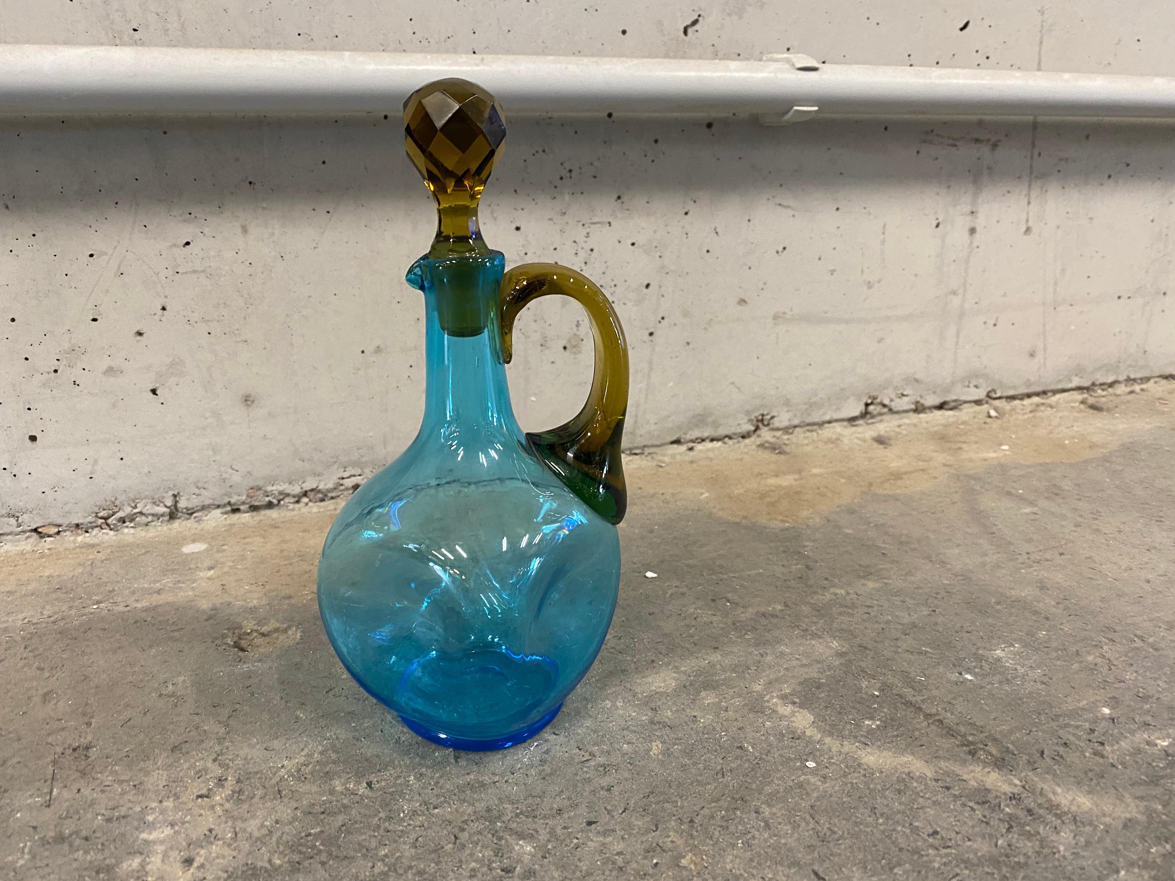 Antique small stopper carafe from France from the years around 1900. The carafe has a bulbous body and opens into a narrow neck, which is closed by a stopper in the form of diamond stones. The mixture of green and blue clear glass makes this carafe