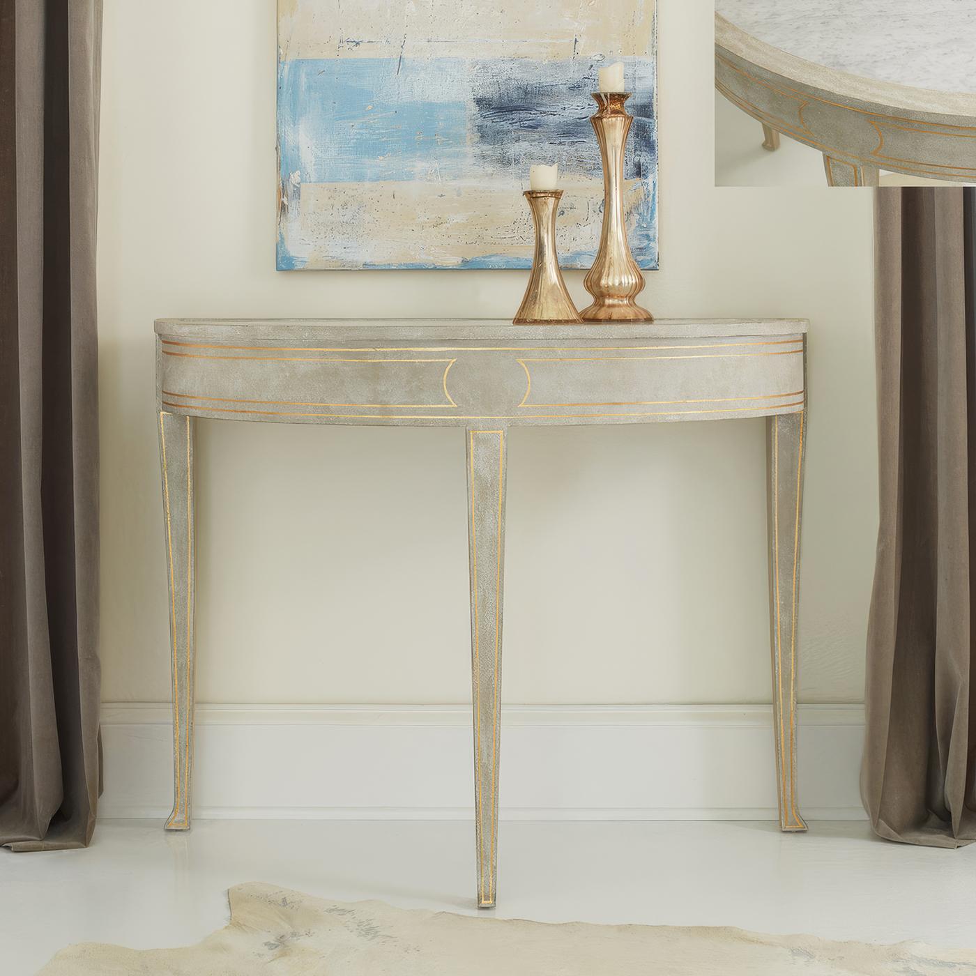 Combining elegant simplicity with fine craftsmanship and luxurious materials. The inset Carrara marble top creates a striking contrast against the hand-applied gray finish, while delicate gold leaf trim adorns the frieze and square tapered legs,