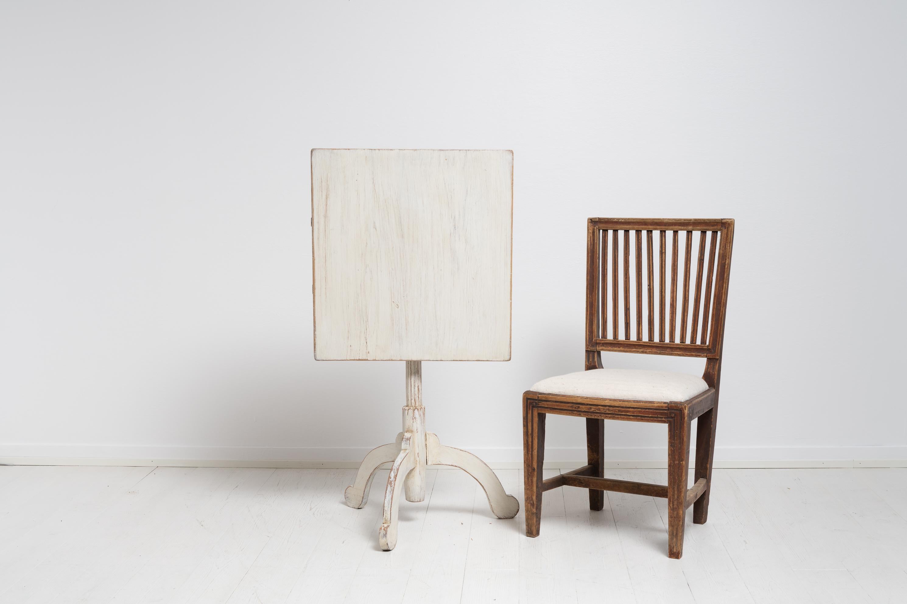Nordschwedischer Säulentisch mit kippbarer Platte aus Kiefer. Der Tisch besticht durch seine Schlichtheit mit weißer Distressed-Lackierung und rustikalen Details. Der Säulentisch hat eine rechteckige Tischplatte auf einem Säulengestell mit drei