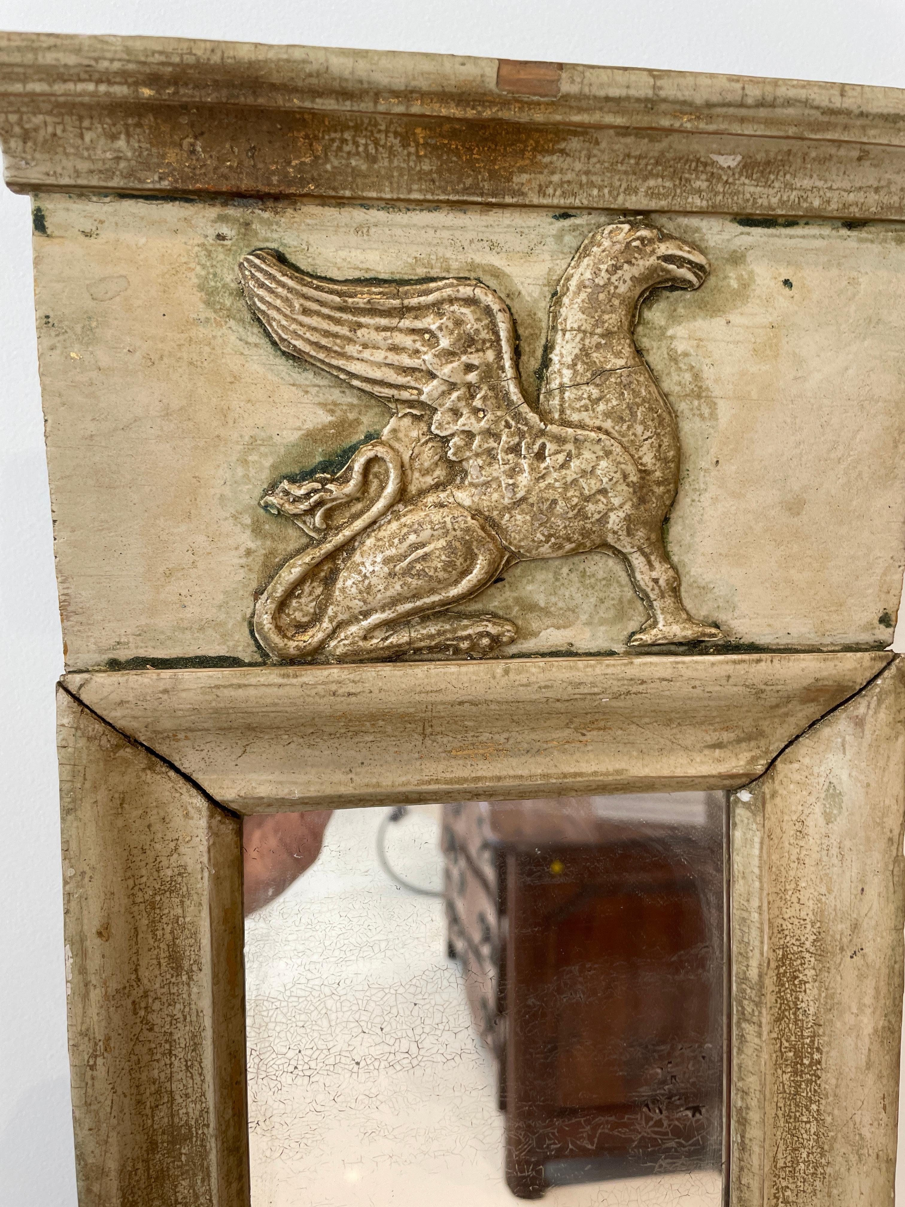 Diminutive in size, but with great presence. This mirror would be perfect in a small powder room or in a grouping. Or, as we have used it, over a small table with a small lamp. The top third shows the full profile of an alert Griffon with curled