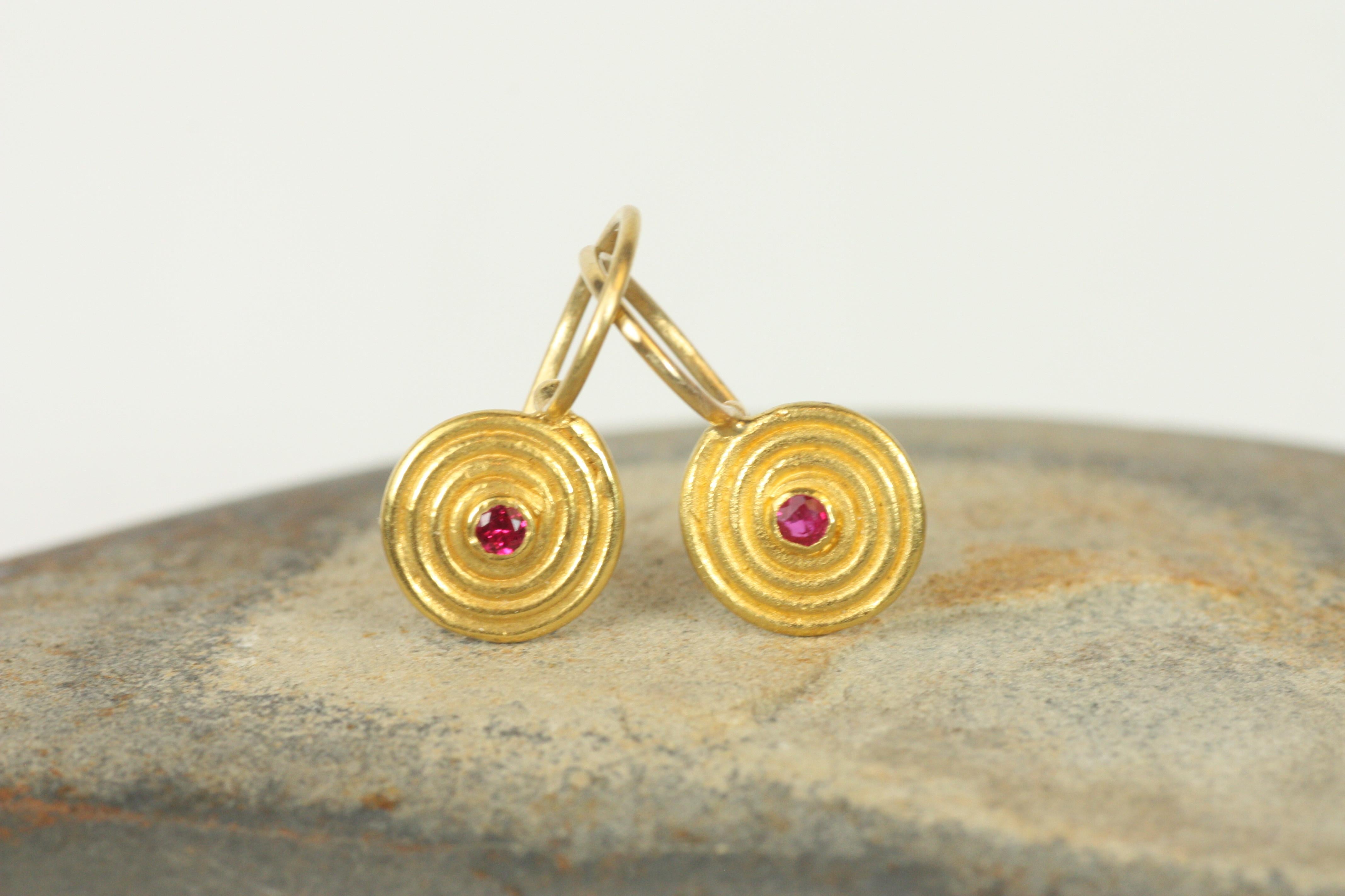 Incarna una bellezza senza tempo con questi piccoli orecchini a spirale con rubini rosso intenso incastonati nell'oro giallo 22 carati. Il design a spirale realizzato a mano riflette l'estetica antica, rendendo questi orecchini una scelta versatile