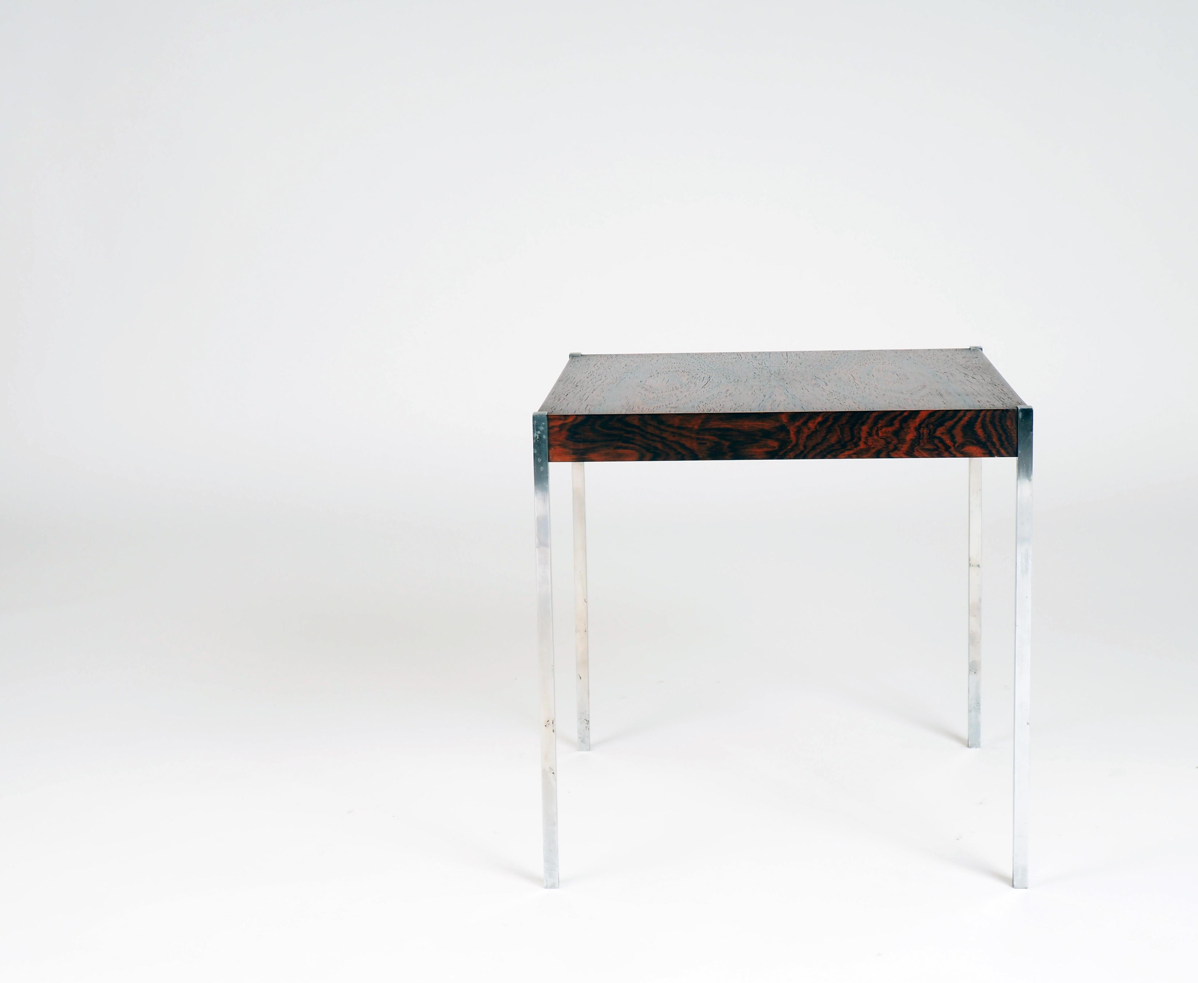 Dieser stilvolle kleine Tisch ist aus Palisanderfurnier gefertigt und hat Beine aus Edelstahl. Es wurde von Östen Kristiansson, einem der Eigentümer von Luxus, Schweden, entworfen.