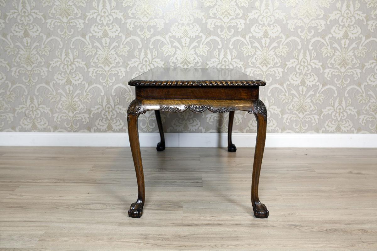 We present you this rectangular small table, circa the early 20th century. 
The whole is placed on bent legs with advanced knees, which are covered with a carved pattern, and claw-and-ball feet. 
The edge of the table top is finished with an