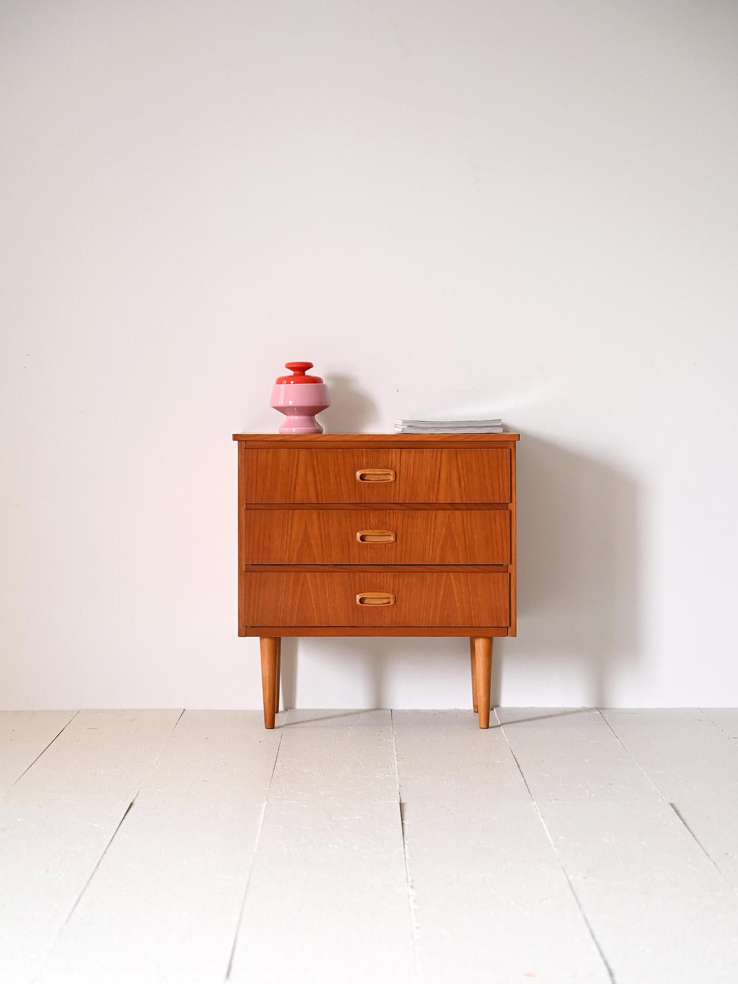 Scandinavian vintage cabinet with three drawers.

This piece of modern antique furniture is characterized by the essential lines and careful details typical of Nordic design. It consists of a teak frame with 3 drawers with carved wooden handles. The
