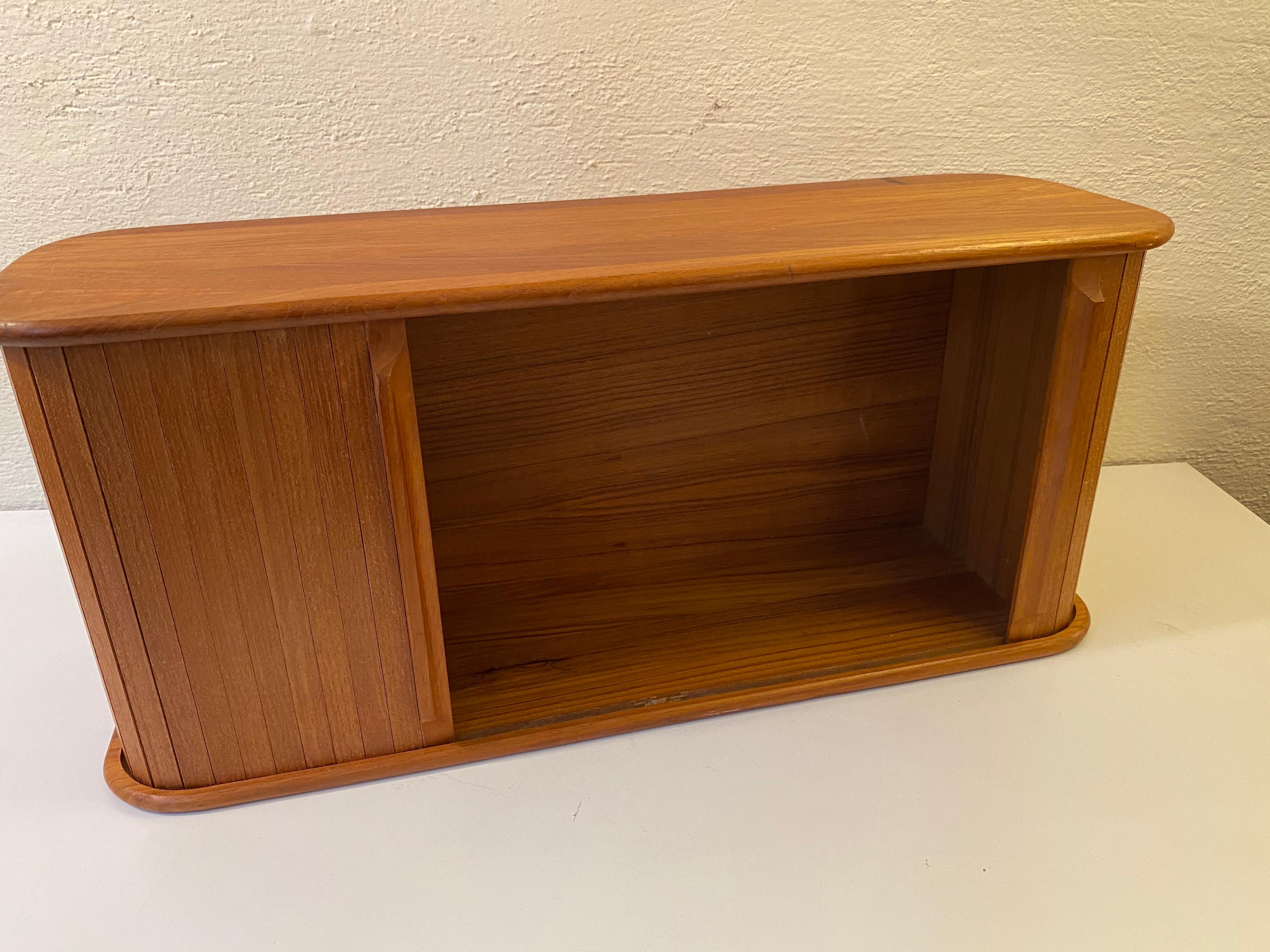 Small tambour door cabinet in teak. Dates from the 1970s by Teak Tech, produced in Thailand. Cut out hooks to back for easy hanging.