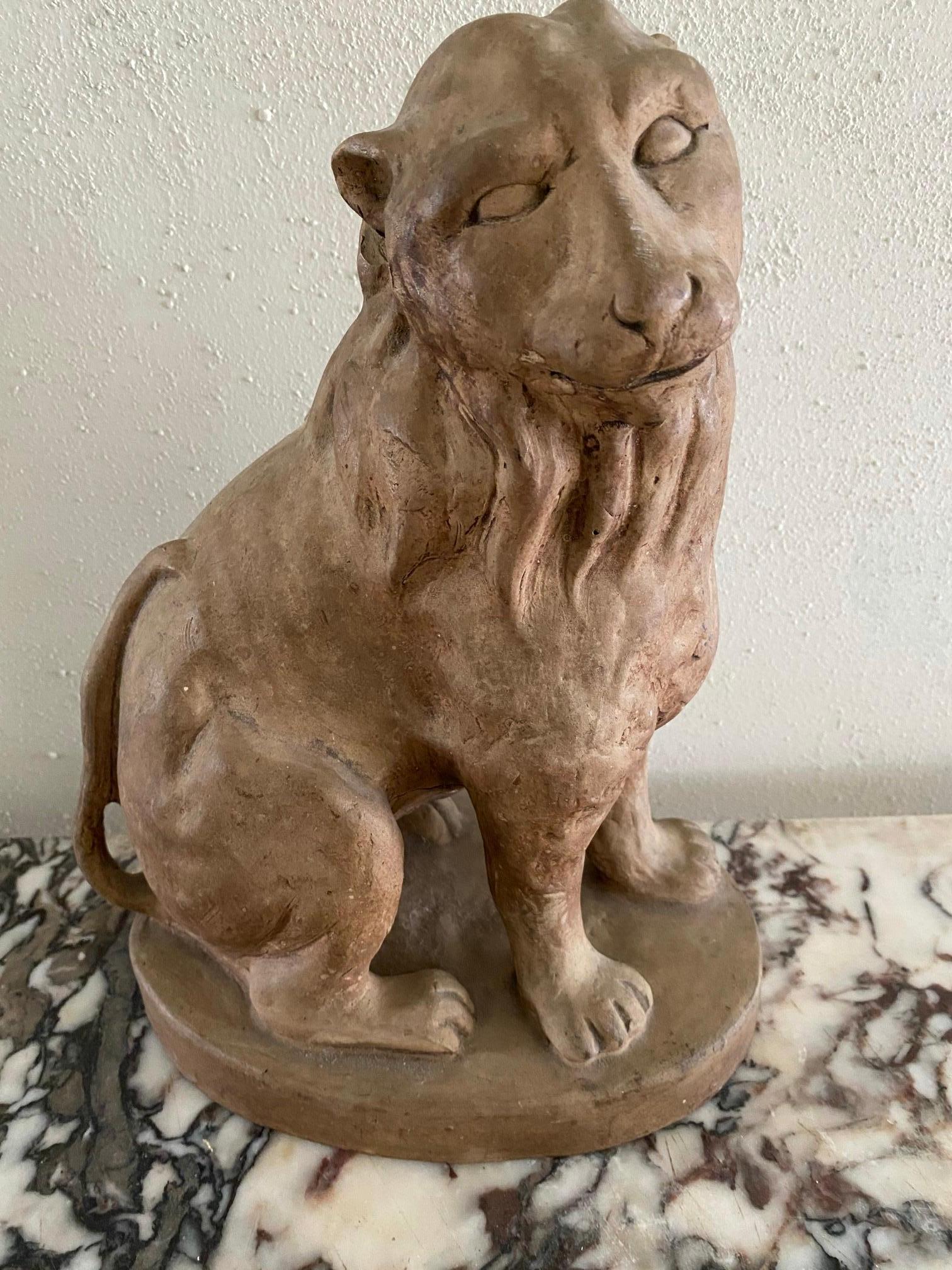 Clay figure of a seated lion with a sweet countenance.