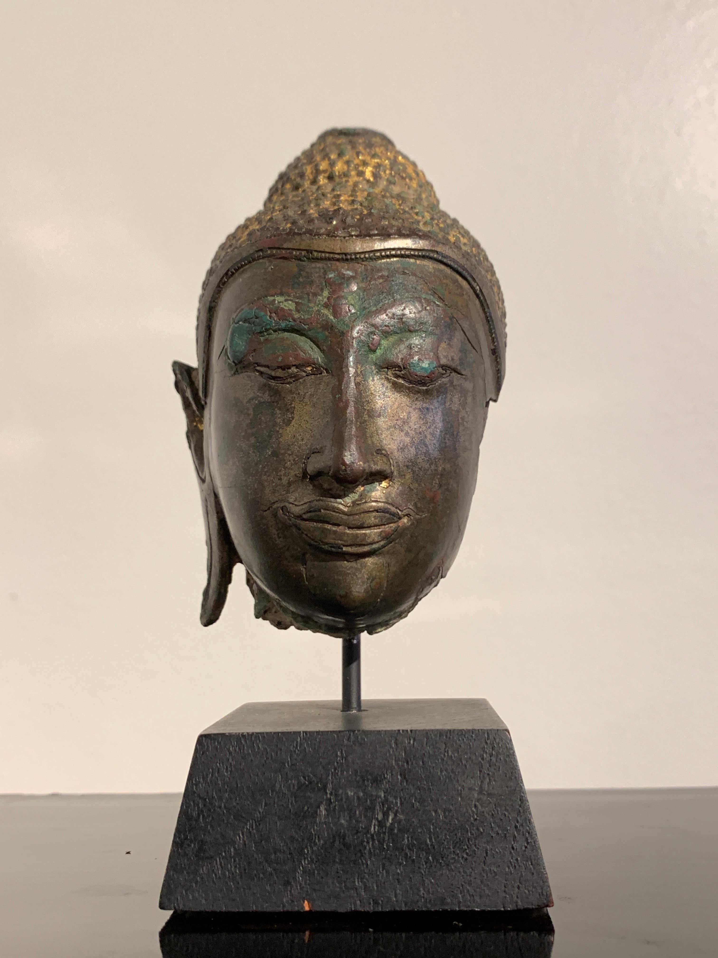 A small and extremely fine fragmentary head of the Buddha, Ayutthaya Kingdom, U Thong B style, 14th to 15th century, Thailand.

The small head of the Buddha cast with striking features, including the aquiline nose, full, pursed lips, almond shaped