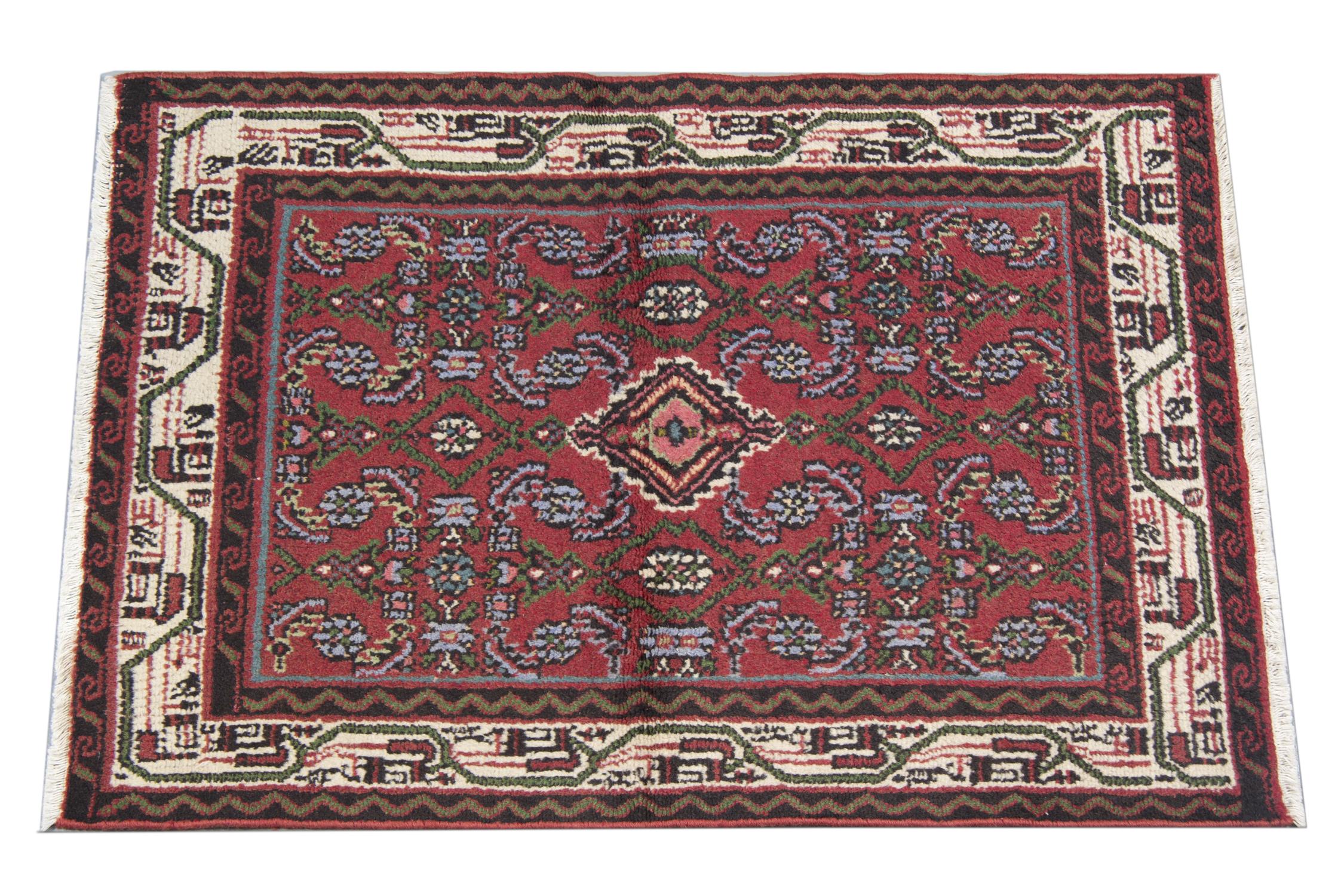 This elegant floral carpet was woven by hand in the 1990s. The central design has been woven on a deep red/burgundy background with a central medallion and symmetrical surrounding design. Repeating pattern borders have then framed this, sure to make