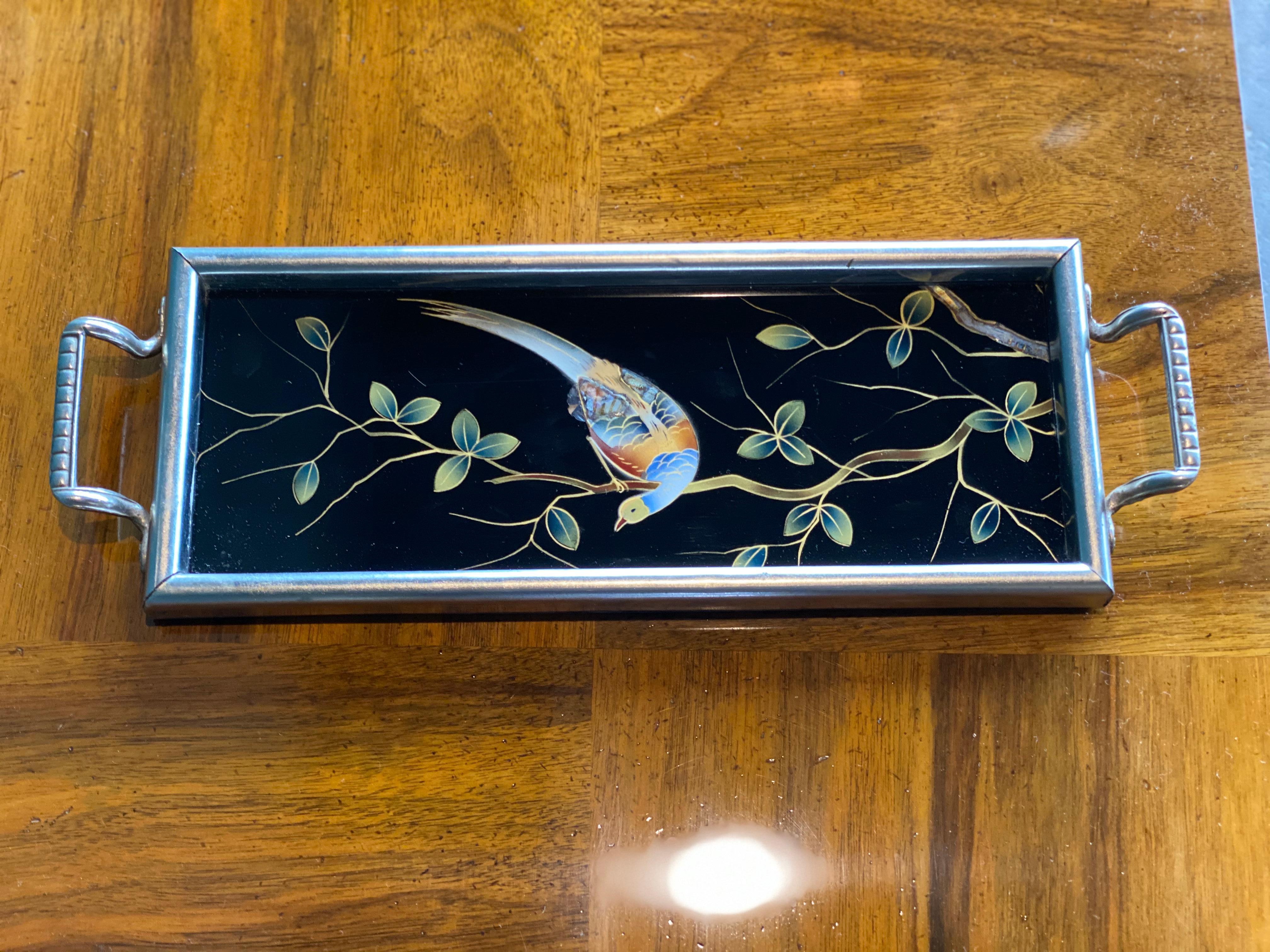 Small Art Deco tray from the 1930s from France. 
Shown is a bird of paradise on a branch, the whole in the style of the chinoiserie. 
The tray is made of wood and framed in metal and has 2 handles. 
On the inside of the frame, the colour has