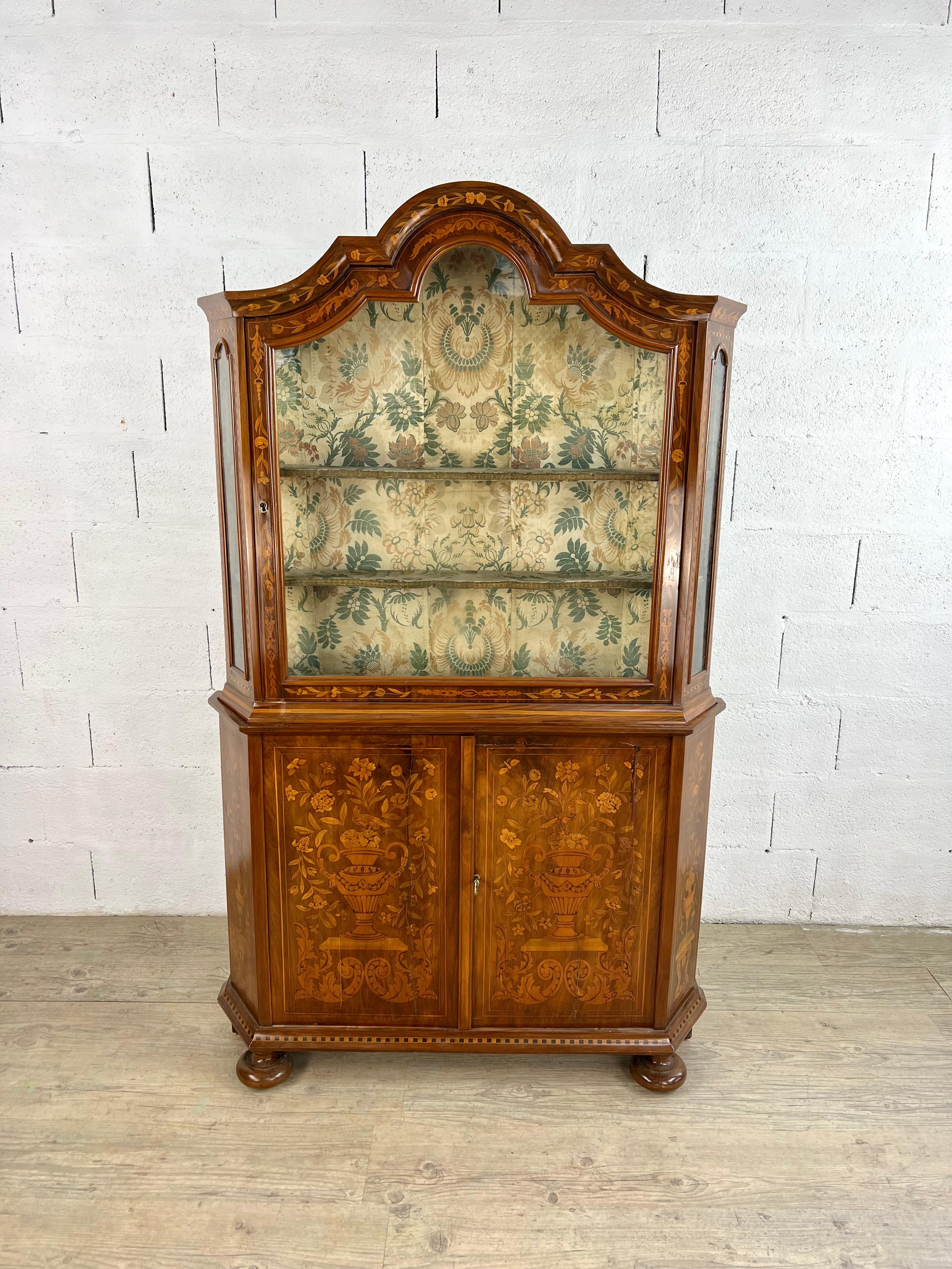 A refined example of Second Empire elegance, this exquisite Dutch two-part display cabinet celebrates the revival of marquetry during the reign of Napoleon III. Crafted with meticulous artistry, its delicate inlays depict Greco-Roman amphorae, each