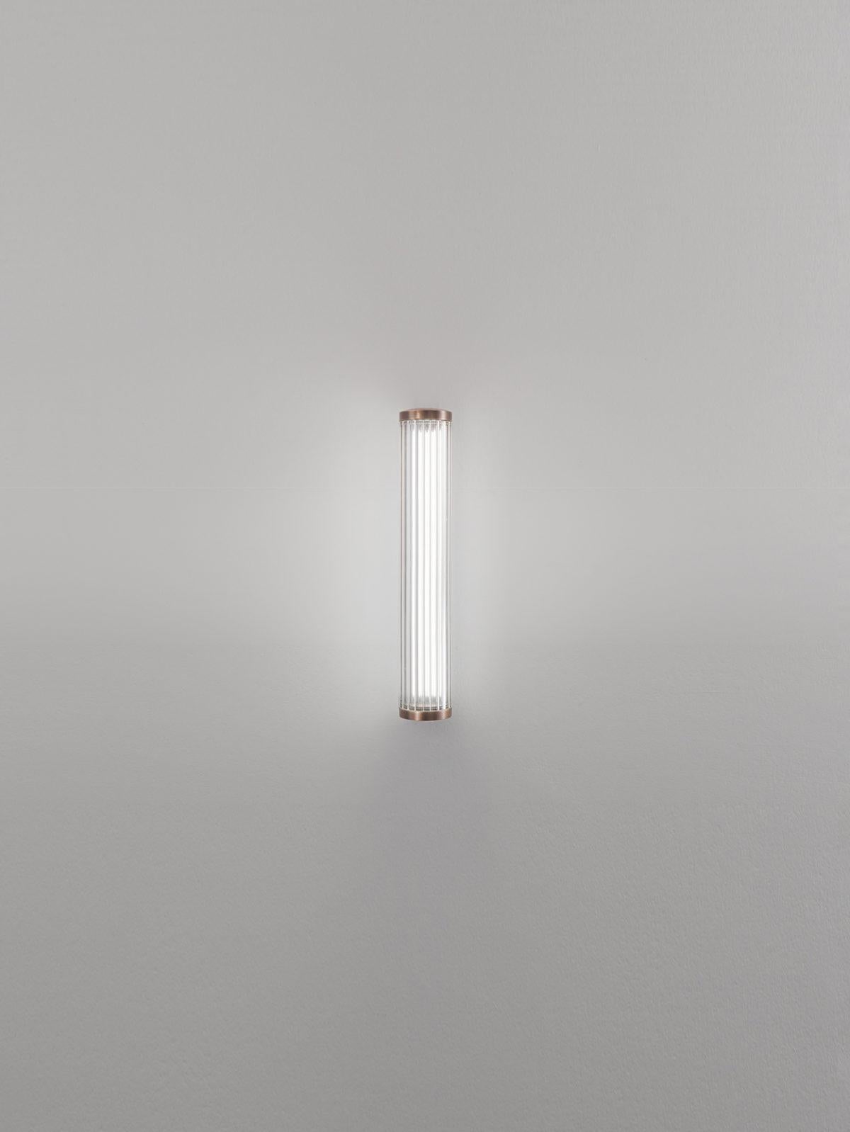 Lampada da parete piccola Vanity placcata in bronzo, rotazione libera a 360°, di Aggiolight
Dimensioni: D 8,2 x L 7 x H 38 cm. 
Materiali: Metallo placcato bronzo antico, vetro soffiato.

Disponibile in altre finiture metalliche.