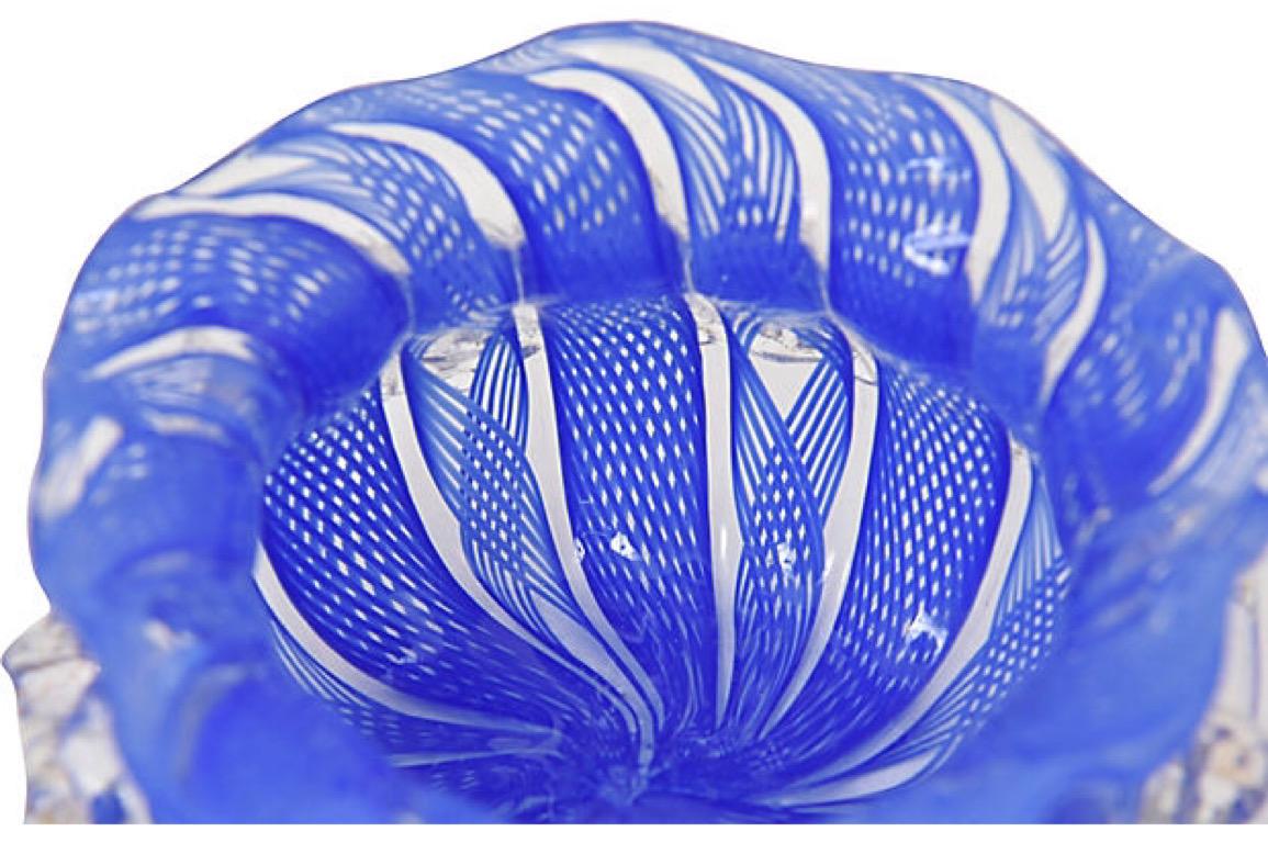Finely made Italian Venetian glass tiny trinket bowl. I would use it for rings. Beautifully designed with a ruffled edge. The bowl itself is blue and clear with an intricate lattice design. On the outer edge there is an applied ribbon design with