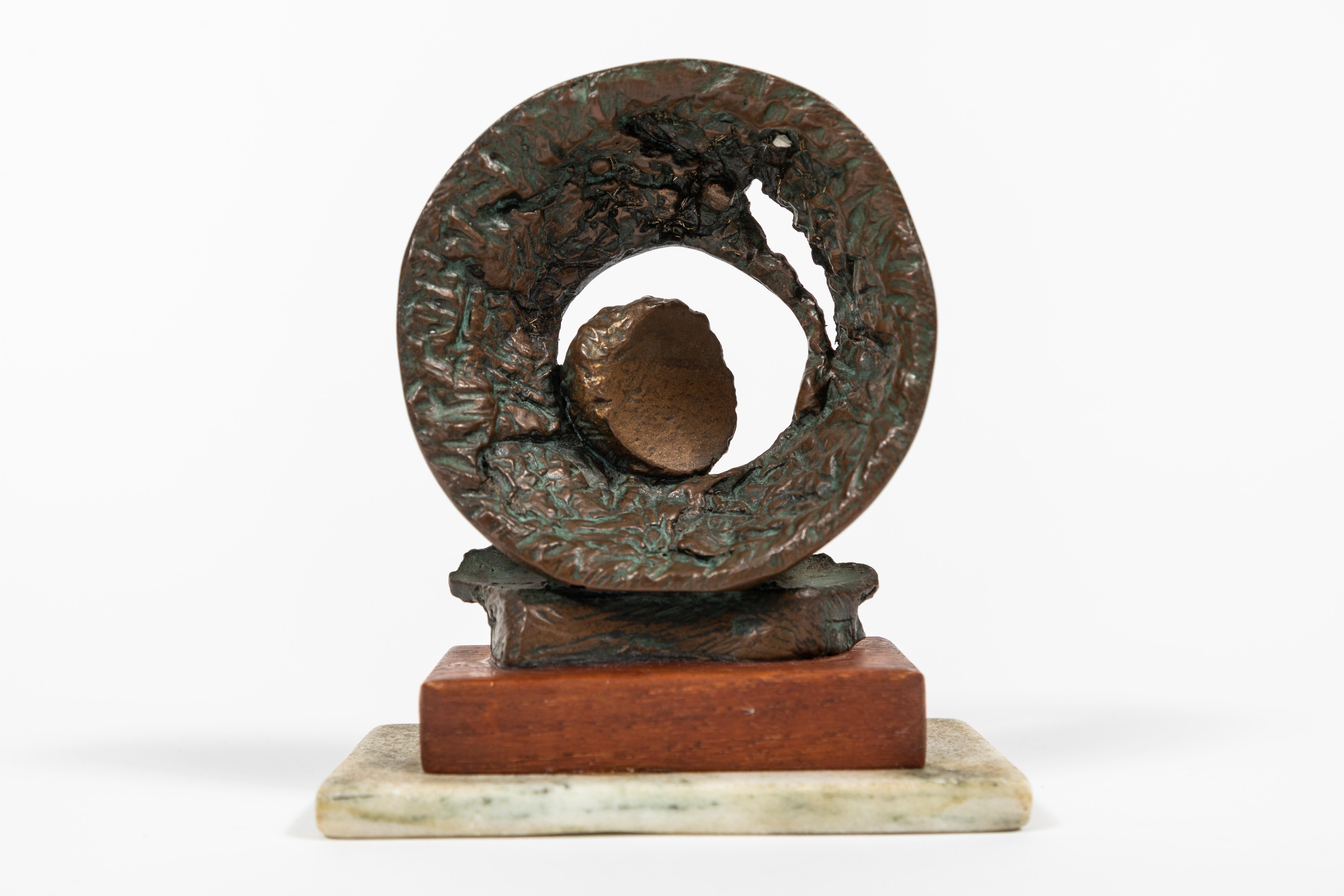 Small vintage circular abstract bronze sculpture with a touch of a verdigris patina and set on a wood and marble base.
