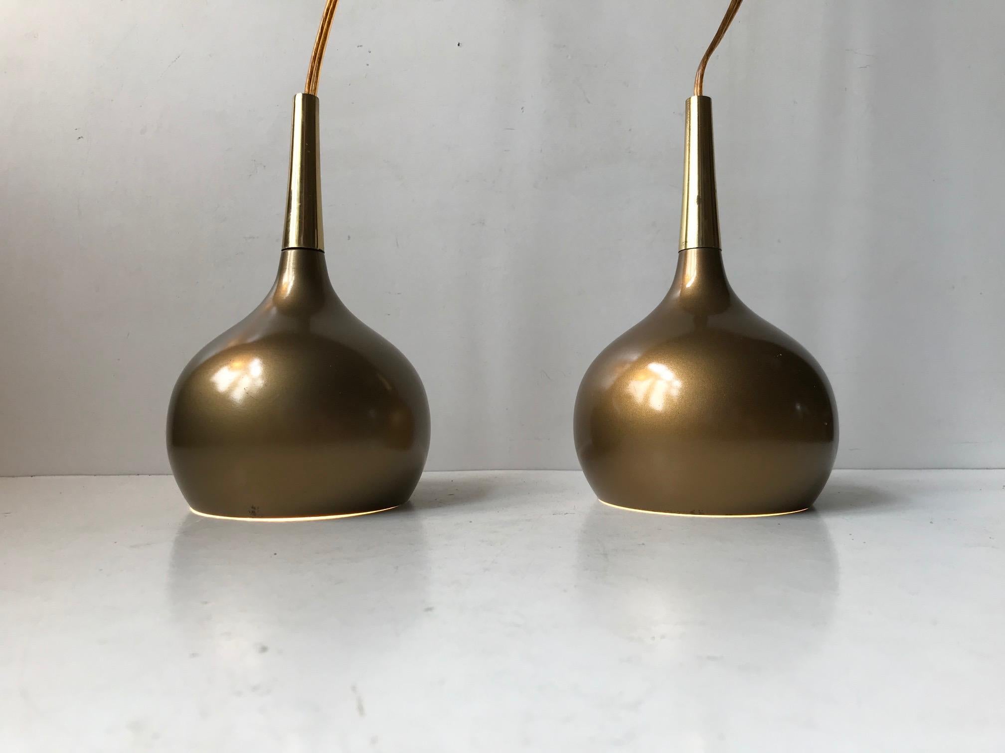 A set of onion shaped pendant ceiling lights by Hans-Agne Jakobsson for Markaryd Sweden, 1960s. They feature a solid brass top/tube and a gold-lacquered shade with white reflective interior. Suitable for kitchen, cosy corner lightning, over your mid