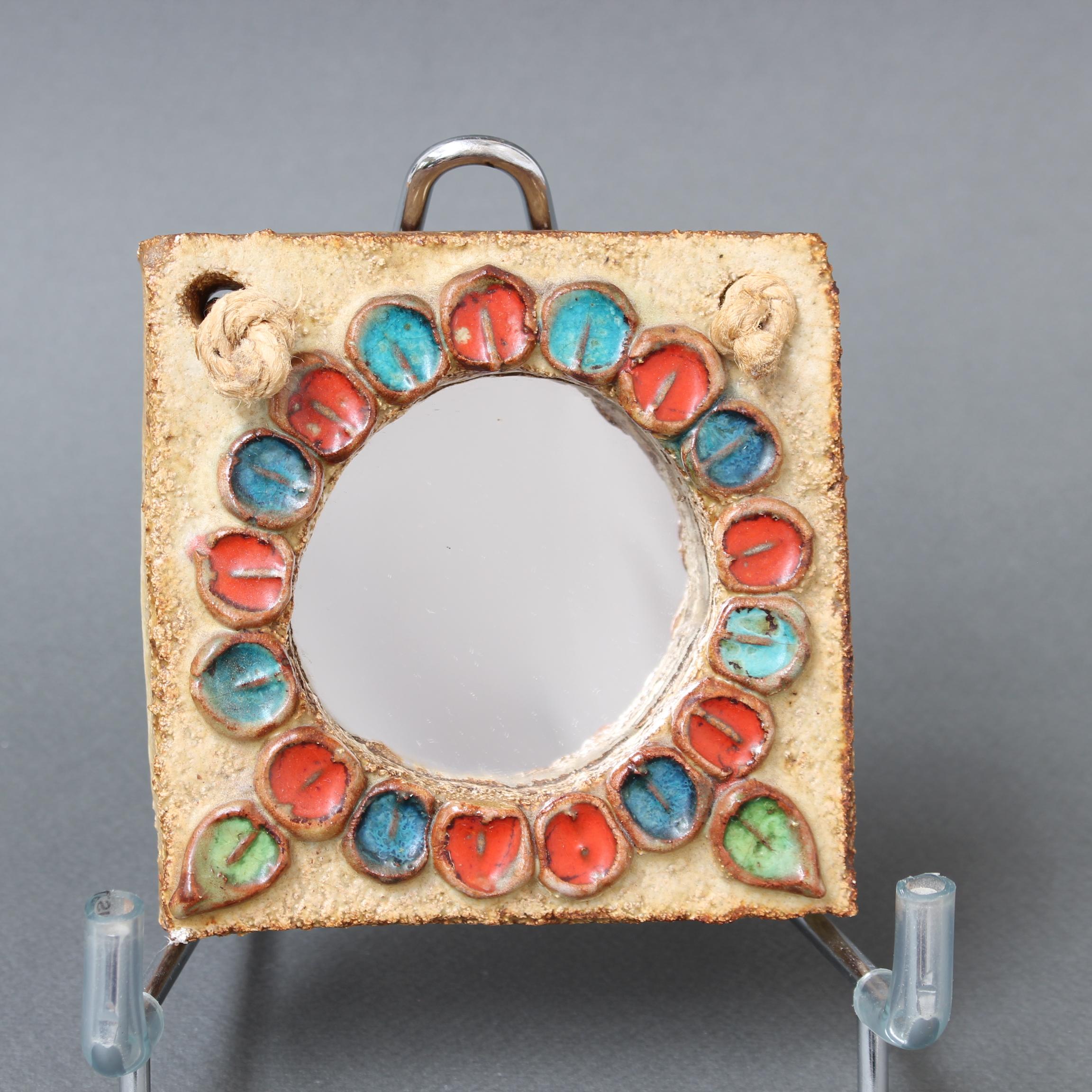 Small ceramic flower-motif wall mirror attributed to La Roue, Vallauris, France (circa 1960s). A charming, decorative mirror with rustic but colourful details surrounding the diminutive round mirror glass. In good overall condition showing