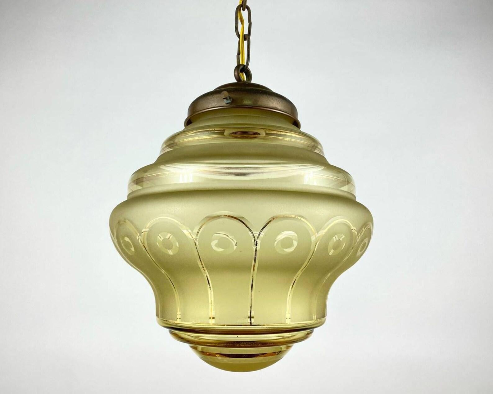 Very nice small glass ceiling lamp.
Art Deco Belgian ceiling lamp with yellow glass shade, 1960s. 

 Stylish Art Deco lampshade is holding on brass structure. 

 The luminaire emits diffused light without glare. Frosted glass provides a very