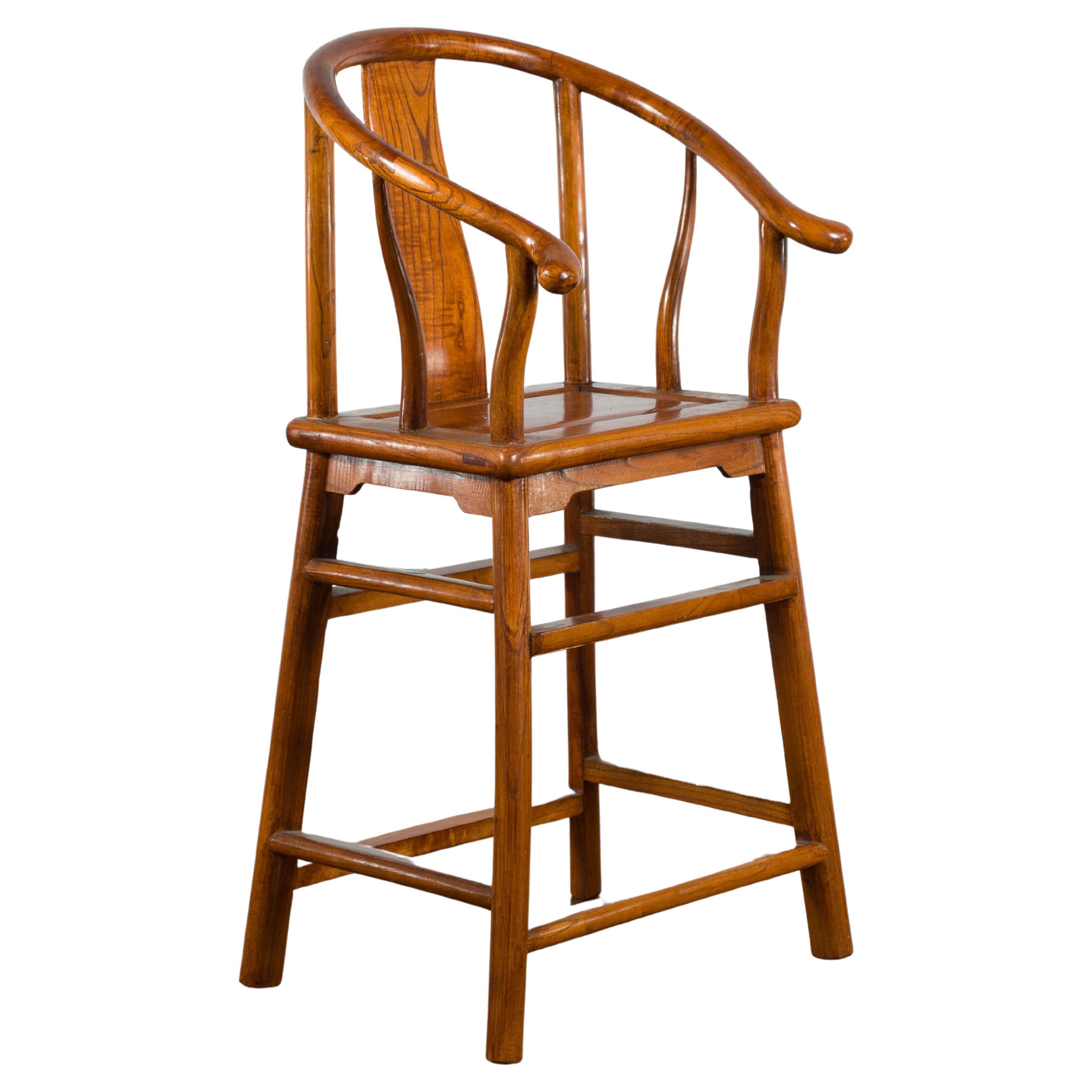 A small vintage elmwood Chinese horseshoe back chair from the mid 20th century, with side stretchers. Created in China during the midcentury period, this small chair features a horseshoe back with curving splat, resting upon a rectangular seat with