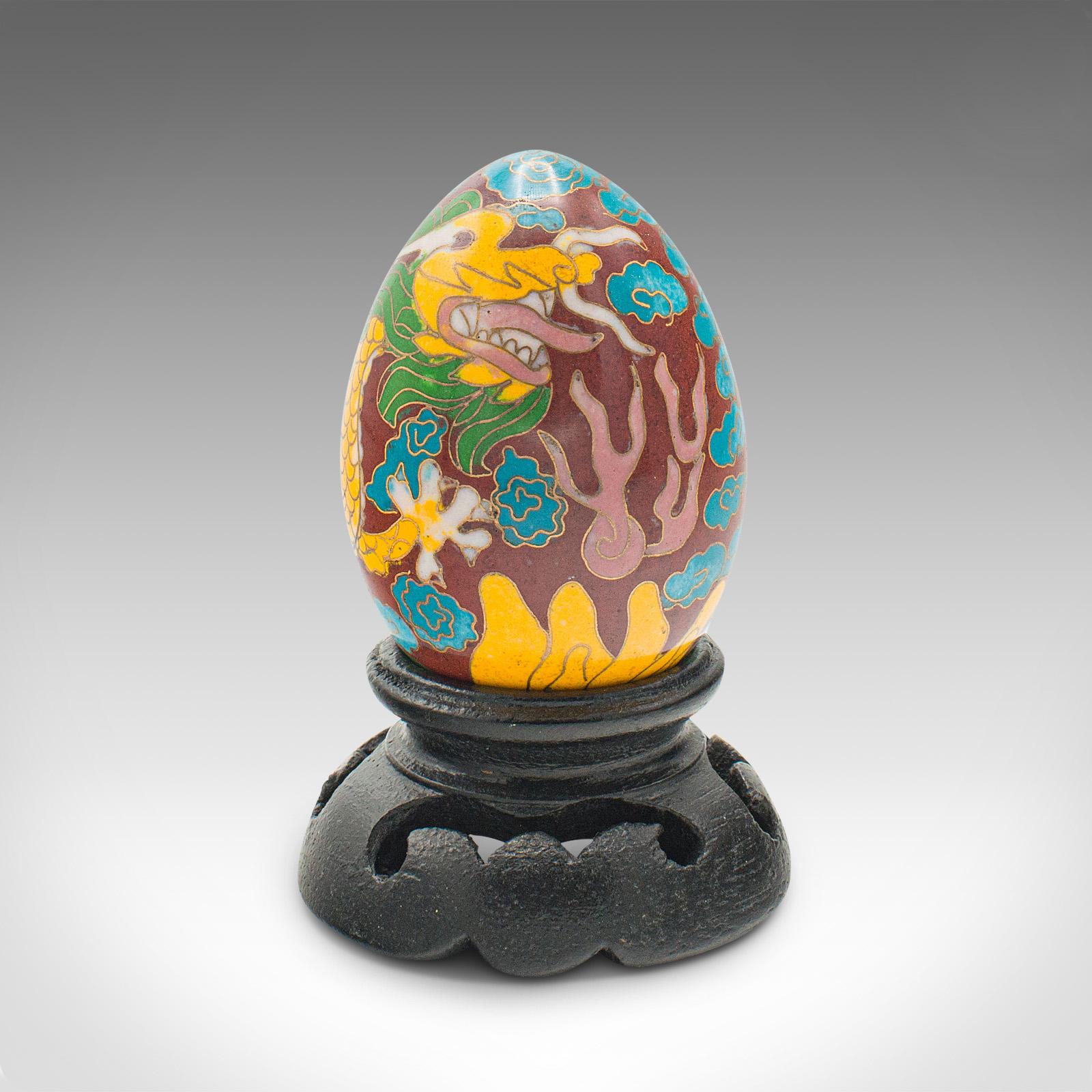 This is a small vintage cloisonné decorative egg. A Chinese, enamelled ornament on ebonised display stand, dating to the late 20th century, circa 1970.

Colourful decorative egg with charming dragon decor
Displays a desirable aged patina and in