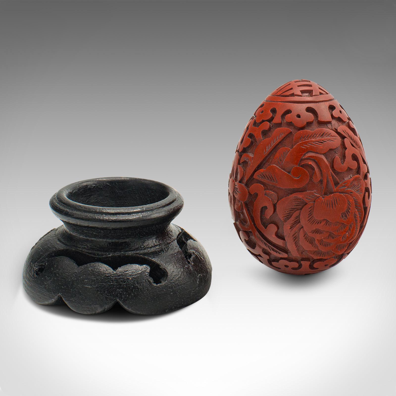 This is a small vintage decorative egg. A Chinese, cinnabar ornament on ebonised display stand, dating to the Mid-20th century, circa 1970.

Colourful carved egg with appealing detail
Displays a desirable aged patina and in good order
Striking