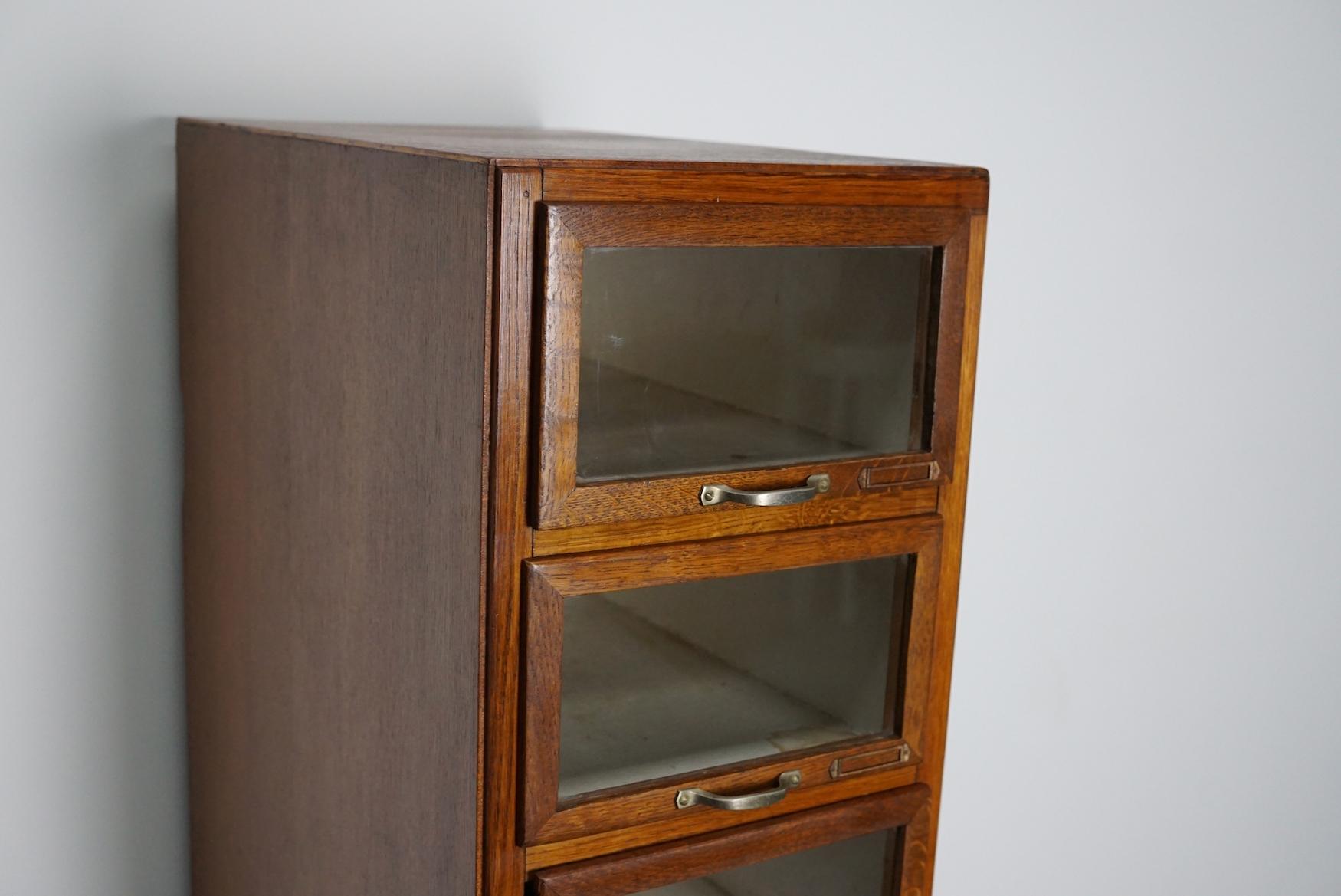 This haberdashery cabinet was produced during the 1930s in the Netherlands. This piece features 8 drawers with oak / glass fronts and metal hardware. It was originally used in a shop for sewing supplies and fabrics in Amsterdam. The interior