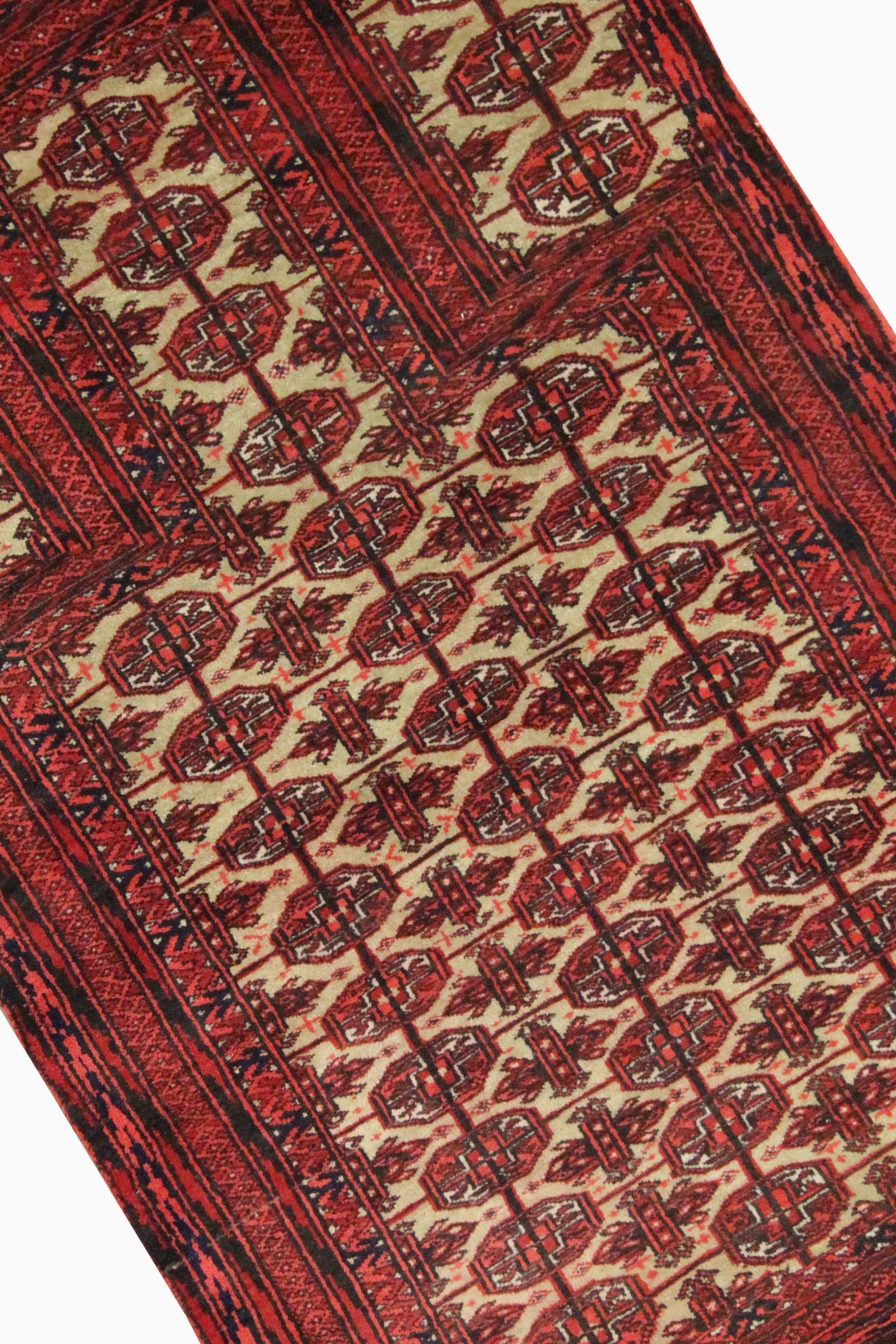 This bold red wool area rug is a fantastic handwoven area carpet constructed in the mid 20th century. The top to bottom design features a traditional geometric pattern woven with red accents on a green-cream background through the centre. This is