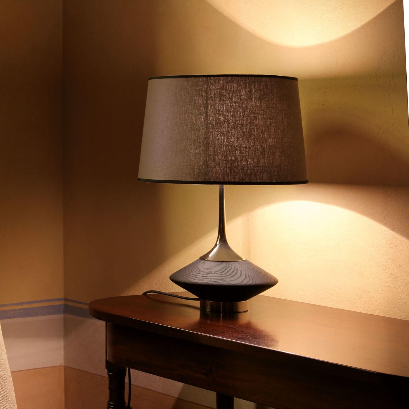The Vuvu wood table lamp is a celebration of natural wood, with veins, cracks and holes ensuring that no two pieces are exactly alike. The stem and base of the lamp are crafted in brass with a polished nickel finish and topped with a linen shade,