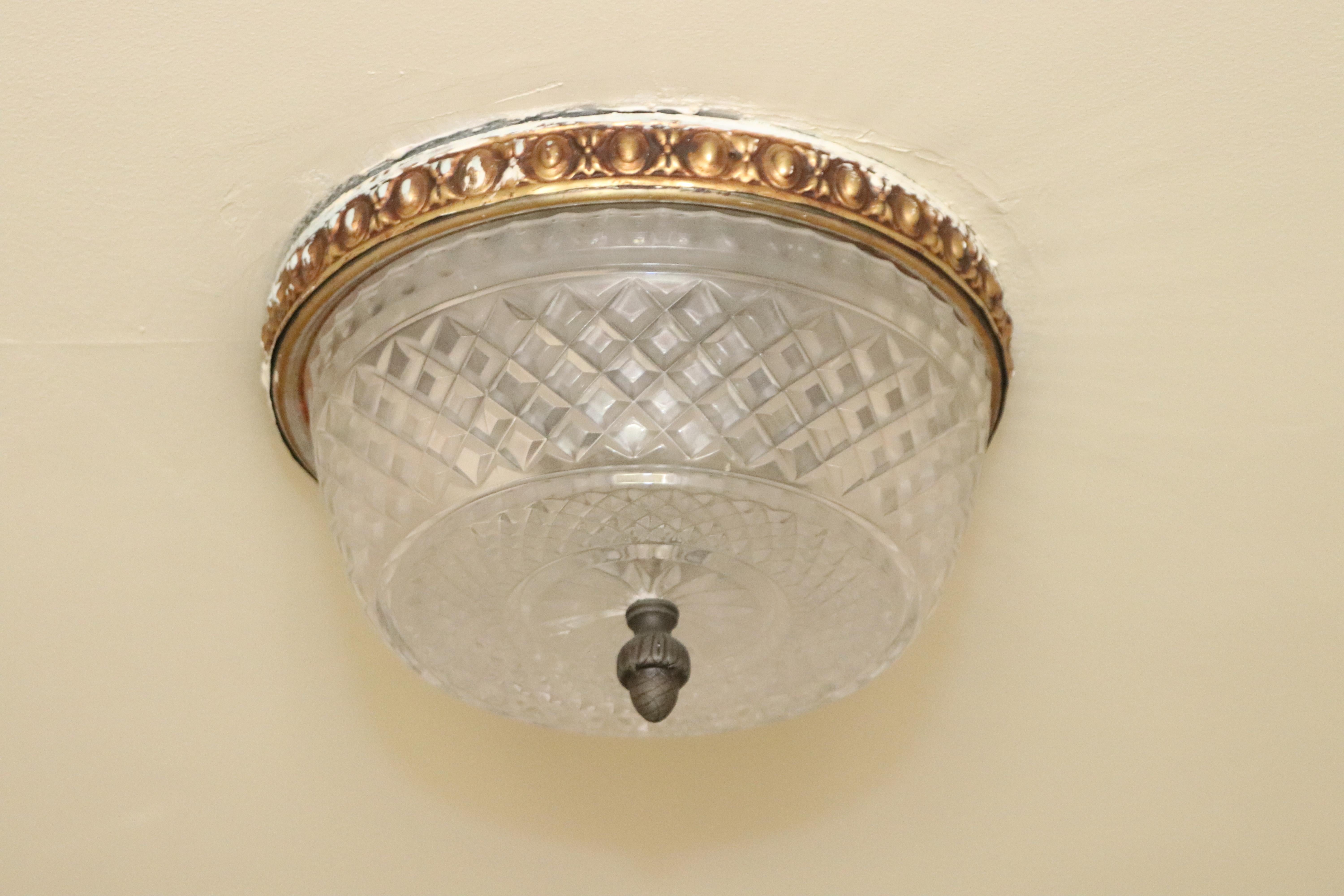 Petite small flush mount light fixture with clear diamond cut crystal and an ornate brass rim. These lights adorned various corridors throughout the NYC Waldorf Astoria Hotel. Possible variations of the rosette and finial. Waldorf Astoria