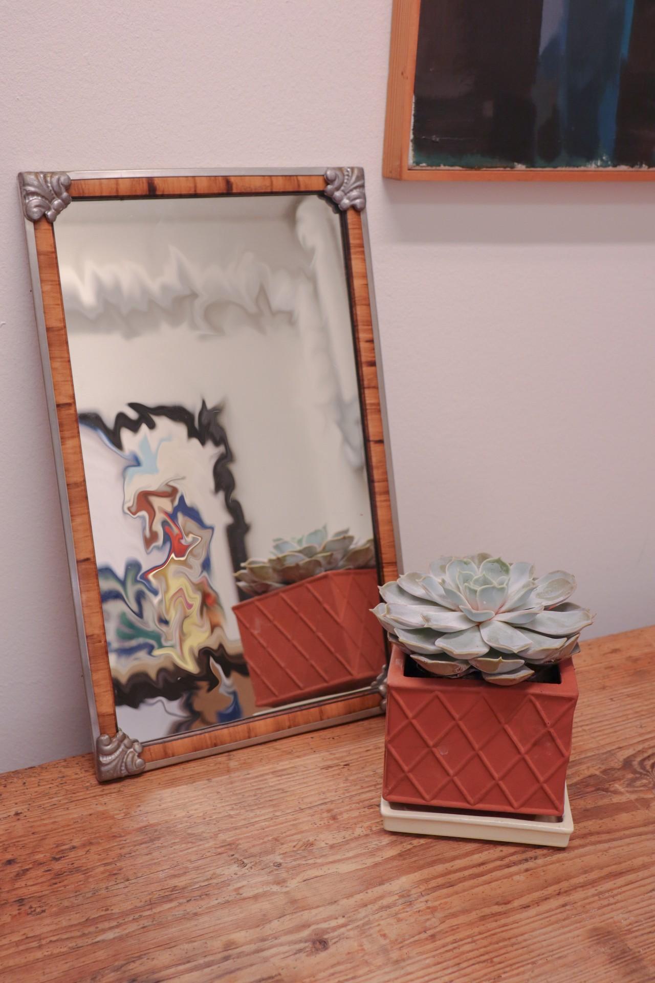 A mirror from the Swedish Grace-period from the 1920s. The mirror has a lovely wooden border with an pewter frame. It is 43,5 x 26 cm and in excellent condition. 