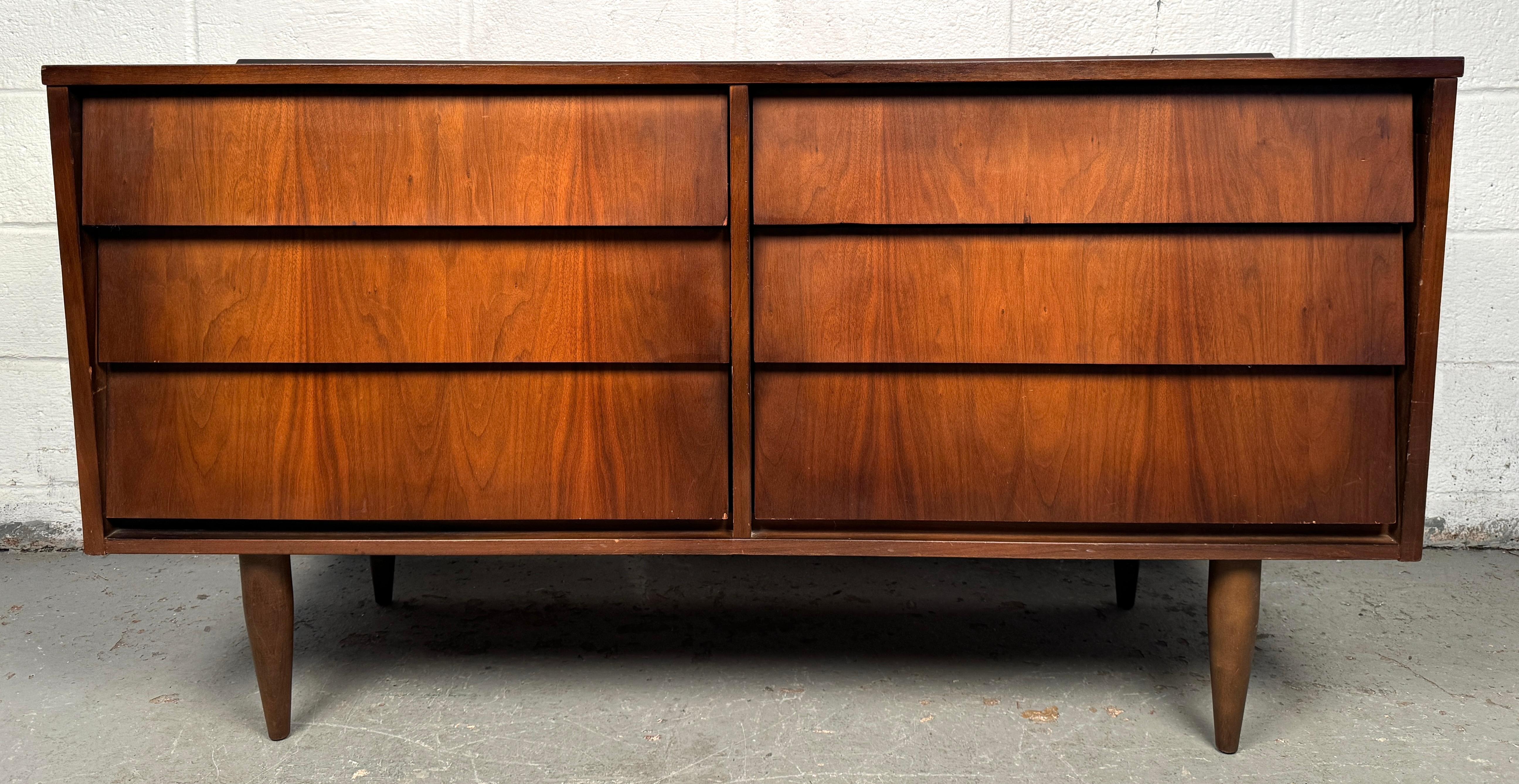 Un'affascinante cassettiera in noce moderna di metà secolo, caratterizzata da linee pulite, ricche venature del legno e proporzioni compatte. Questo pezzo versatile offre cassetti multipli con tiretti minimalisti, che lo rendono ideale per gli spazi