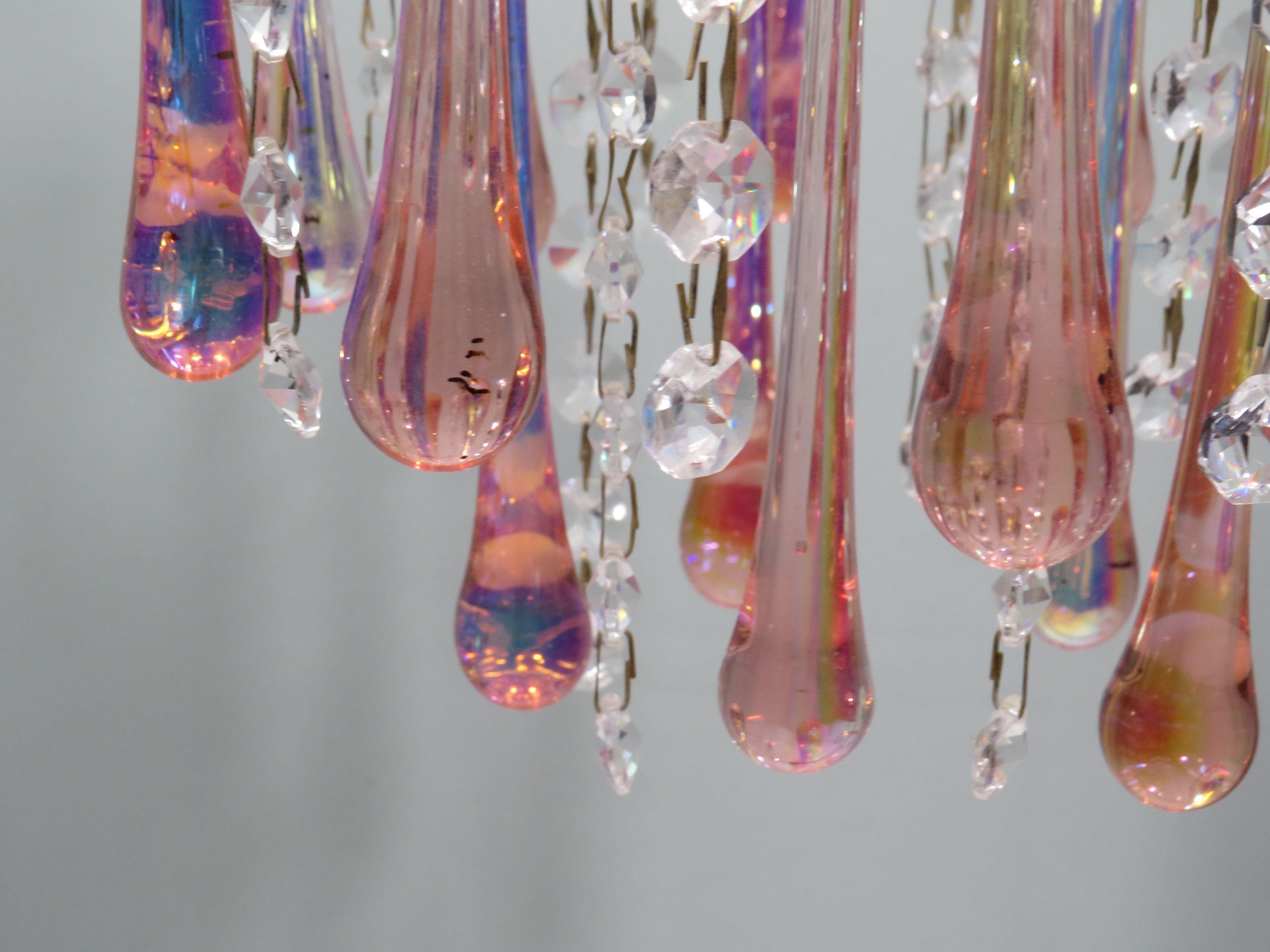 This delicate vintage pendant combines pink-hued Murano glass with radiant crystal strands for a unique mix of playful elegance. The gold-coloured frame and matching chain create a graceful and refined look. Ideal for soft, atmospheric lighting