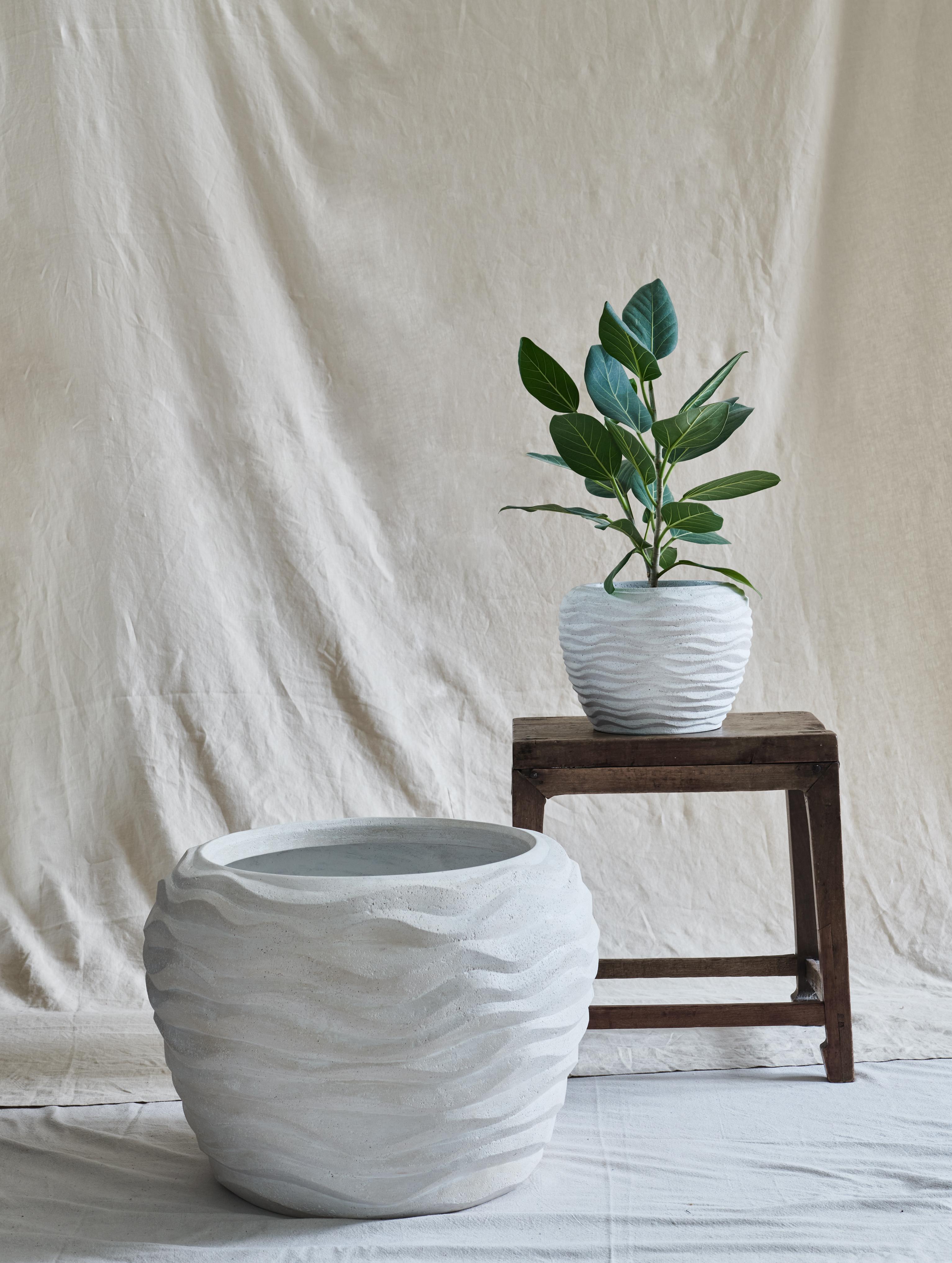 A small, stout, and round vessel with a wavy imprinted texture, reminiscent of the undulating petals of a carnation flower. 

For indoor or outdoor use.

Dimensions (in): 11