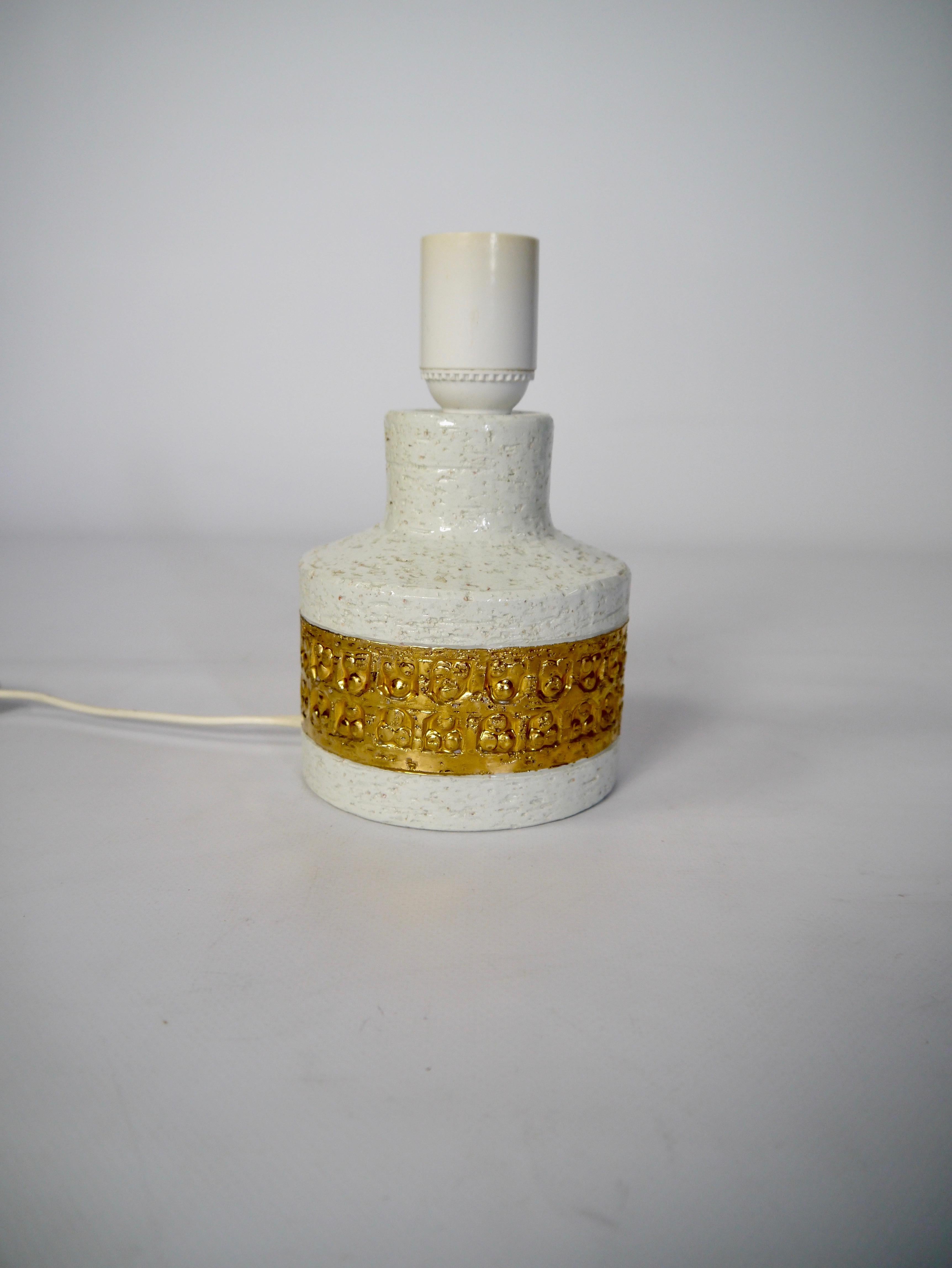 Piccola lampada da comodino/tavolo di Bitossi, con l'emblematica texture rustica in bianco sporco e la cintura dorata. 