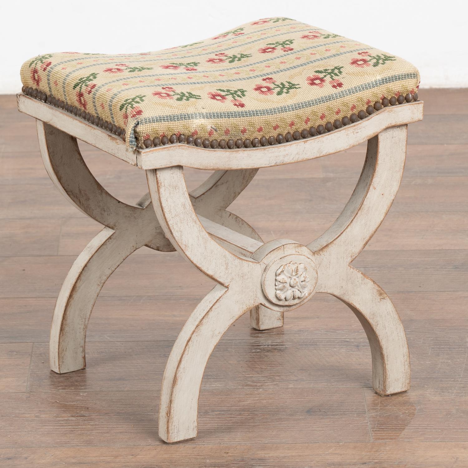 This petite Swedish stool or tabouret has a yoke shaped base with applied carved flower medallion.
The distressed patina of the later antique white painted finish adds to the charm.
This small stool or footrest still has the original worn and