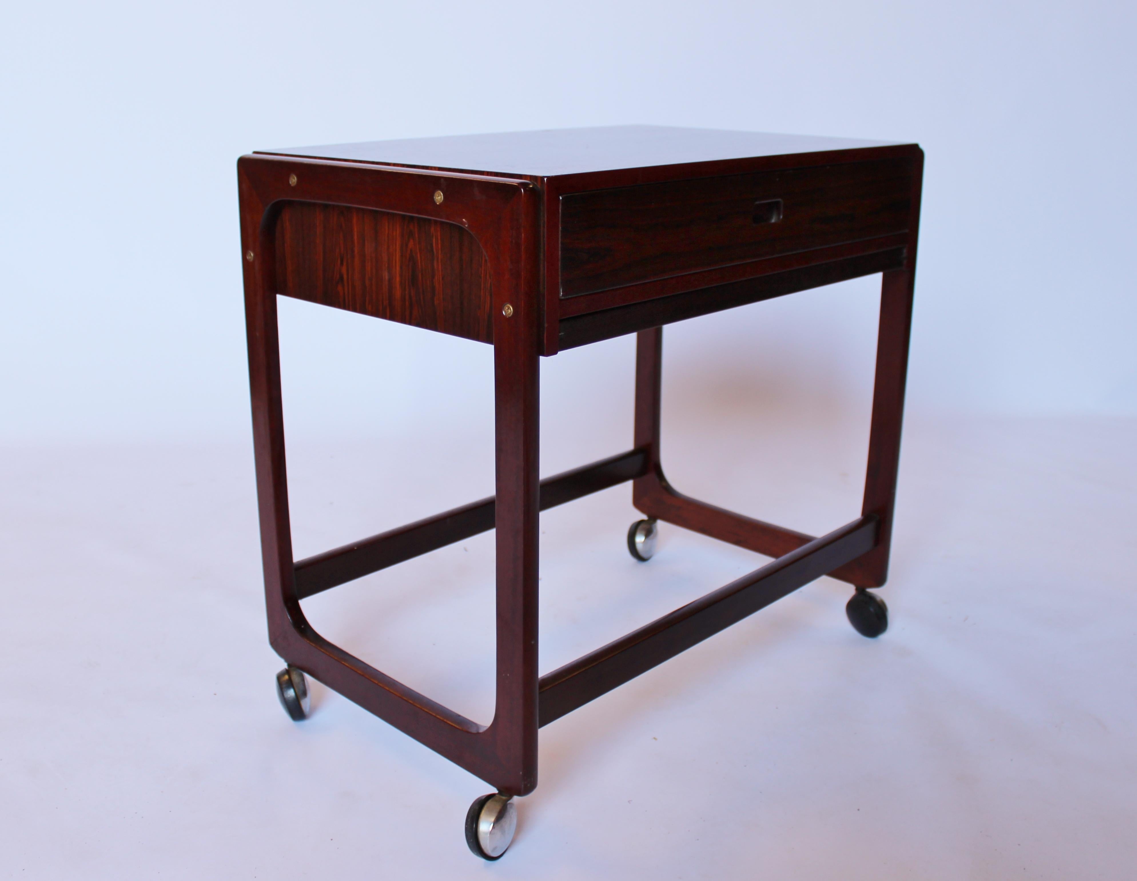 Questo tavolino da cucito emana la classica eleganza e funzionalità che caratterizza il design danese degli anni Sessanta. Realizzato in palissandro, un materiale noto per il suo colore caldo e le sue bellissime venature, il tavolo aggiunge