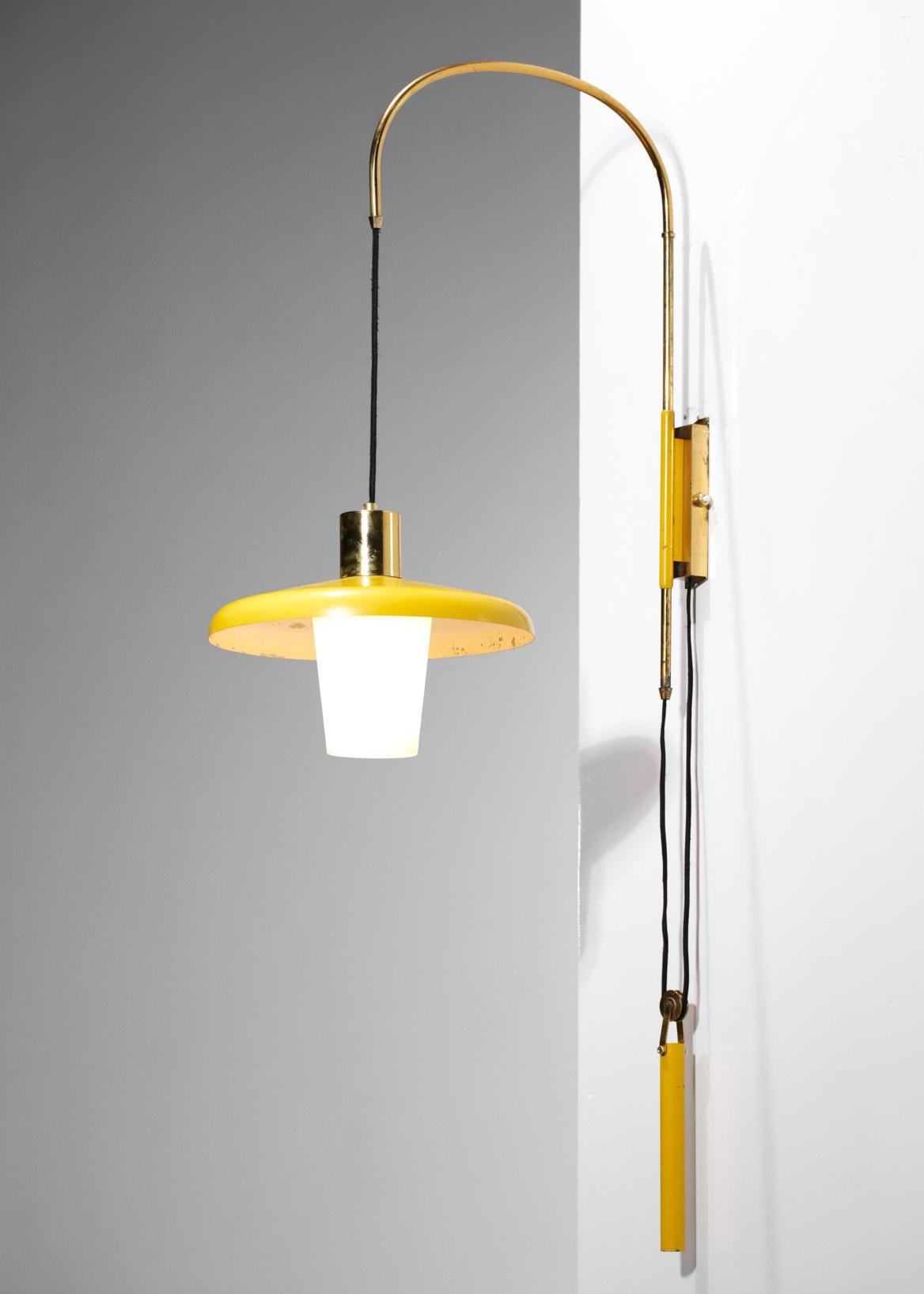 Small Italian wall lamp of the 50's attributed to Stilnovo. Structure in solid brass, lampshade, counterweight and wall plate in yellow lacquered metal (original paint). Diffuser in opaque white opaline. Raise and lower system to adjust the height