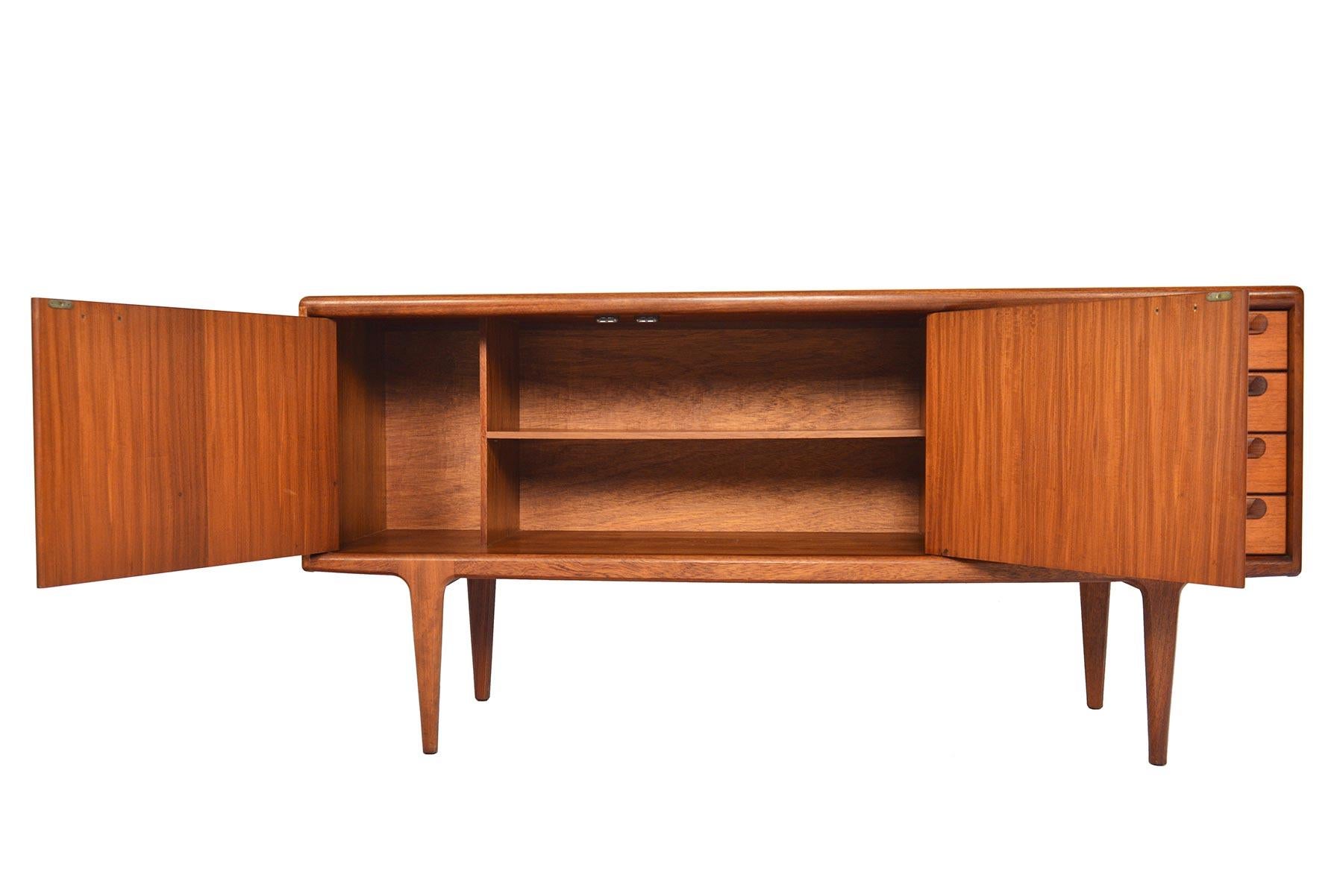This small teak credenza was manufactured by Younger of England in the 1960s. Beautifully sculpted edge banding and handles add dynamic depth to this piece. The cabinet doors open to reveal a fixed vertical divider and an adjustable shelf. Four