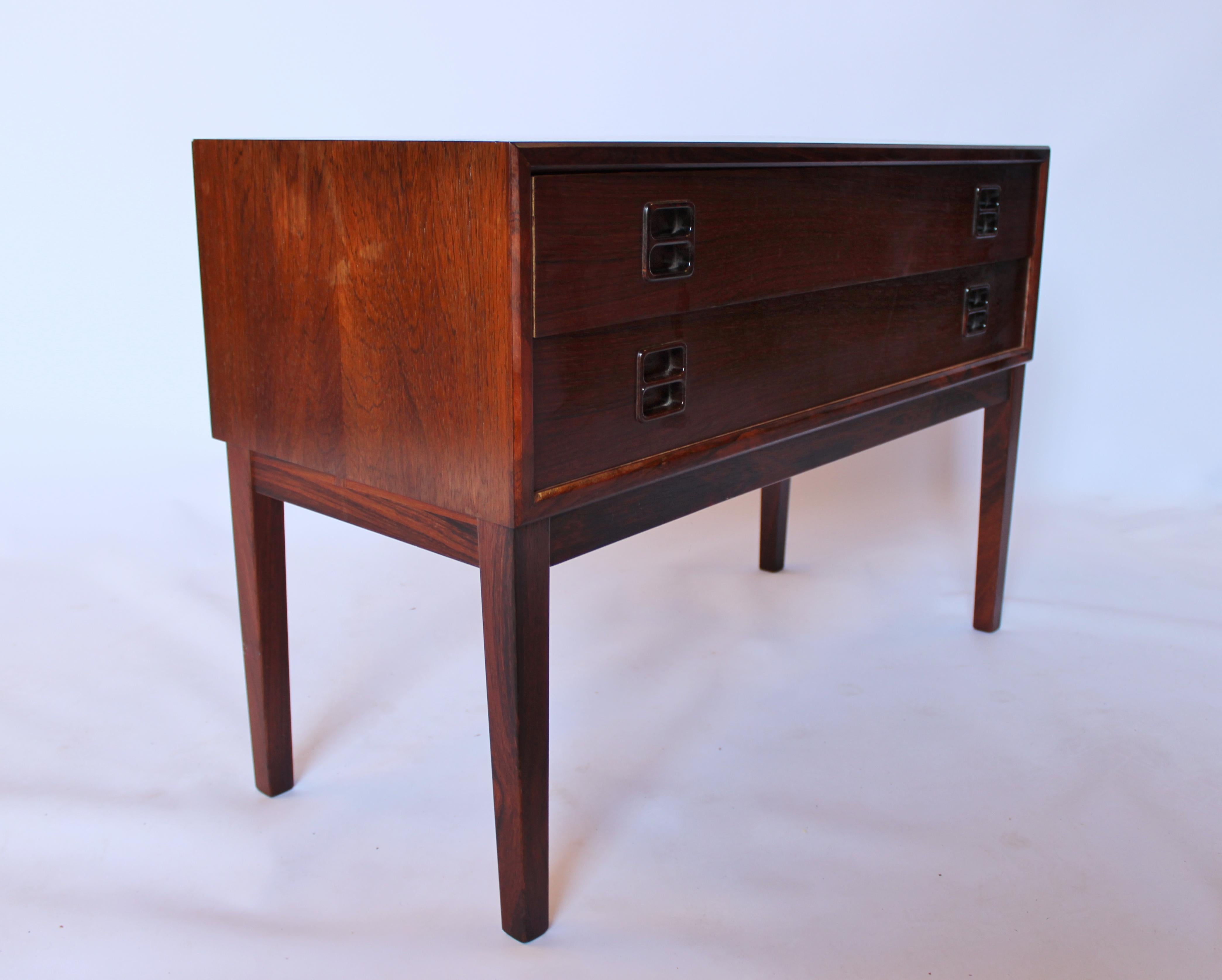 The smaller dresser with two drawers in rosewood, featuring Danish design from the 1960s, is a delightful and practical piece of mid-century furniture.

Danish design from the 1960s is celebrated for its clean lines, functional aesthetics, and use