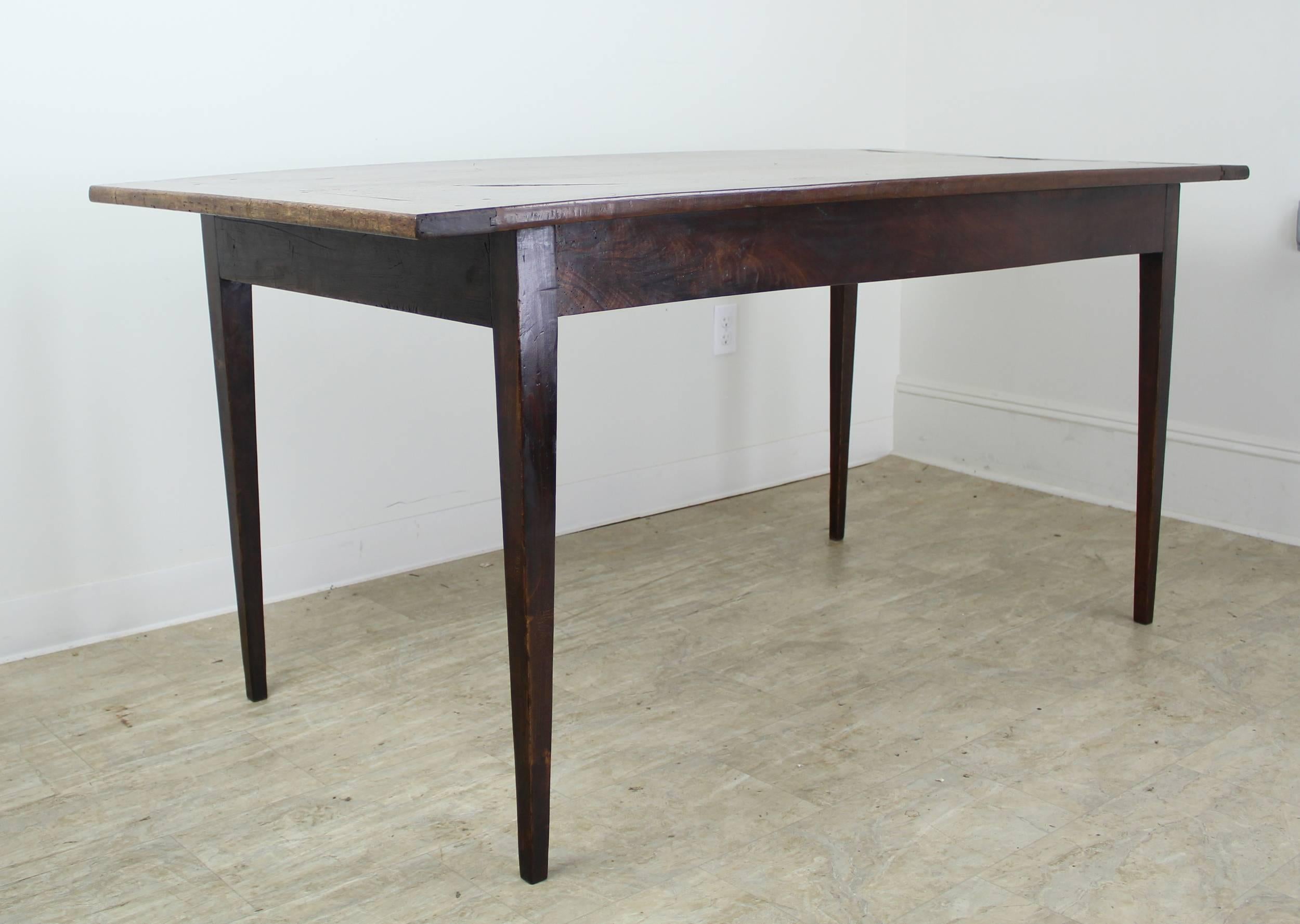 A two plank dining table with spectacular walnut grain and rich color. The breadboards, mild distress and dramatic natural knot hole add visual interest. Dainty tapered legs are elegant and graceful. A true beauty and with 52 inches between the