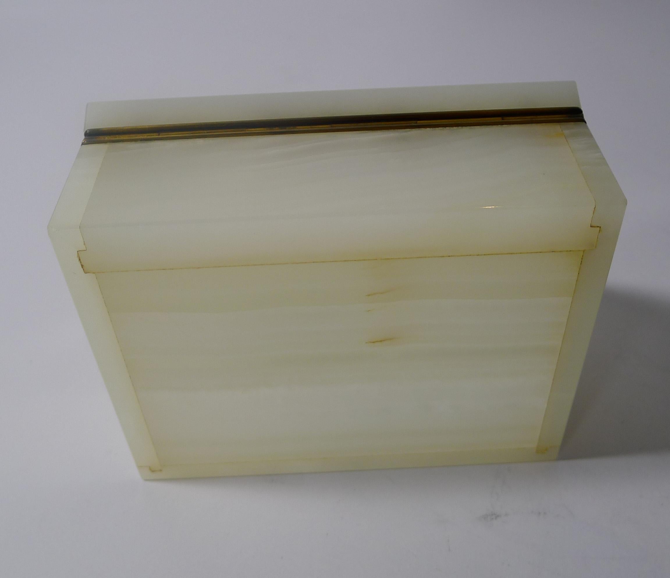 A very elegant box in white Onyx with a flourish of Malachite sitting below the lift at the front.

The box opens to reveal the signature for the well renowned London Patentees and Makers, George Betjemann. Marked on the gilded hinge, Betjemann's