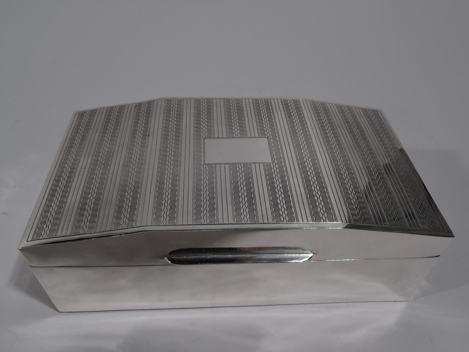 Smart English Art Deco sterling silver box, 1931. Rectangular with straight sides. Cover hinged, tabbed, and gentle faceted. Cover top has alternating engine-turned wavy and lined bands, as well as central rectangular frame (vacant). Box and cover
